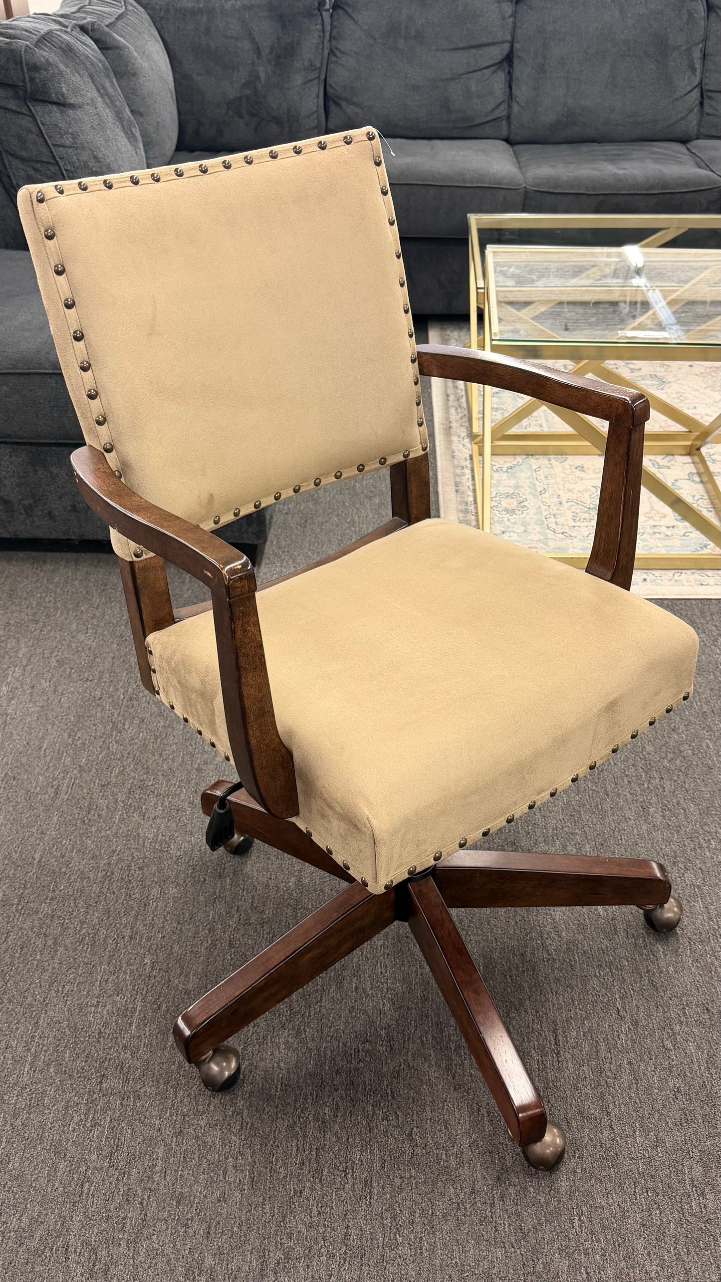 Beige office chair with wooden frame on a gray carpeted floor.