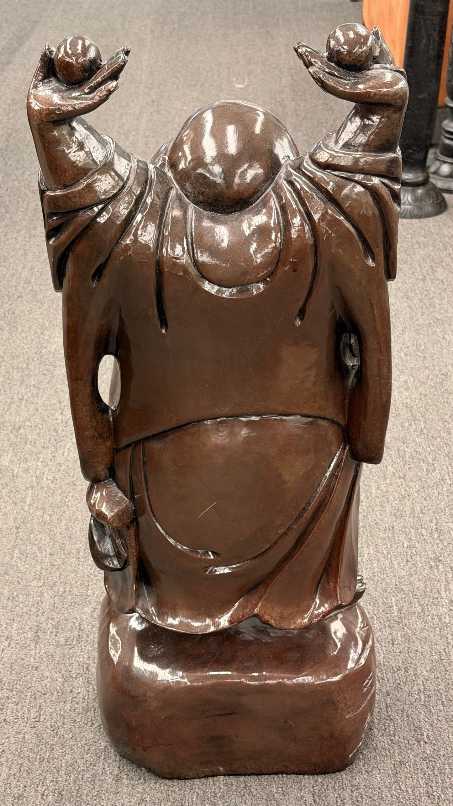 Bronze statue of a figure with outstretched arms on a neutral background