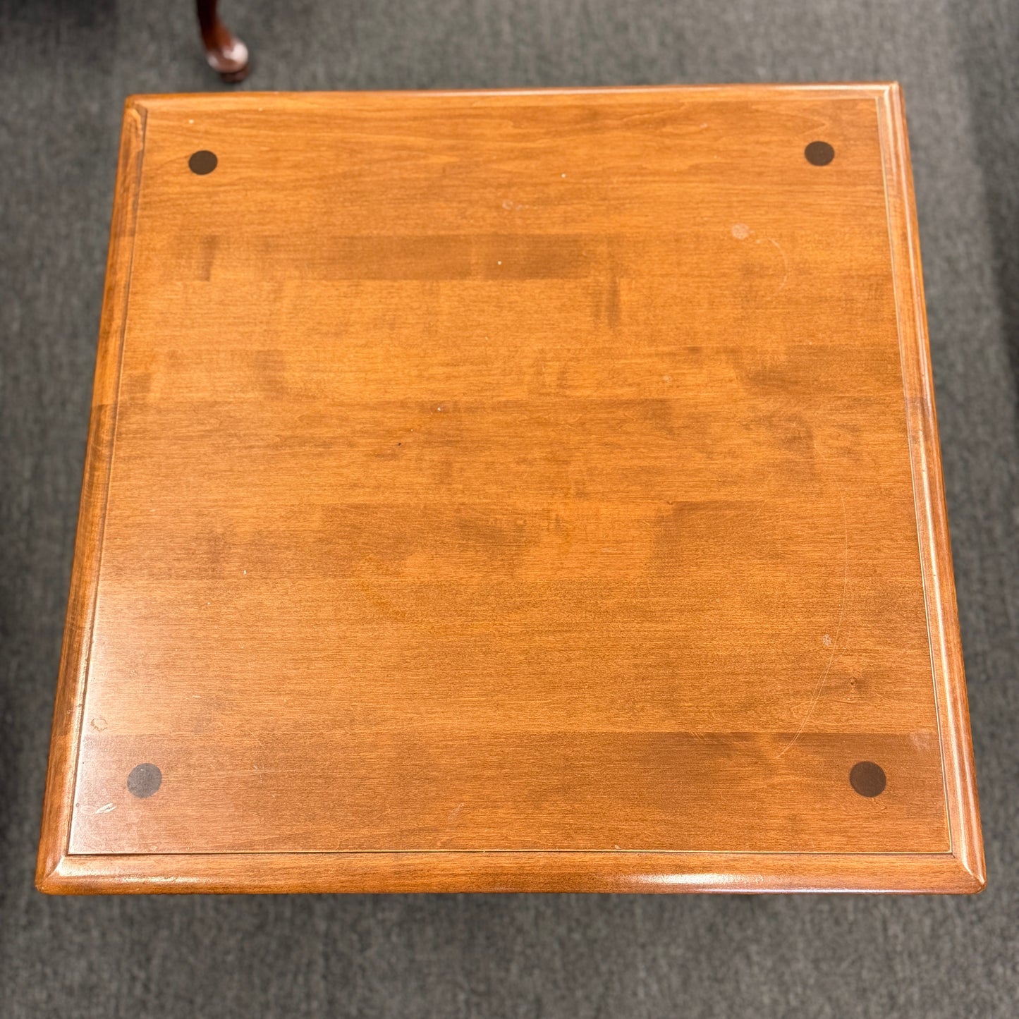 Wooden square object with four holes on a gray background