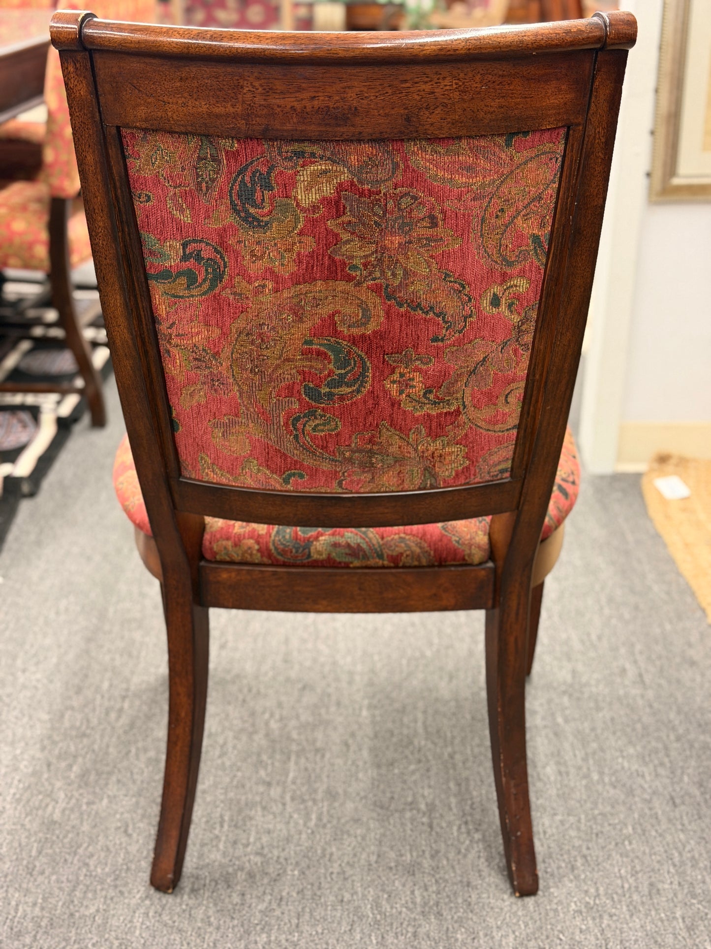 Wooden chair with patterned red backrest on a carpeted floor