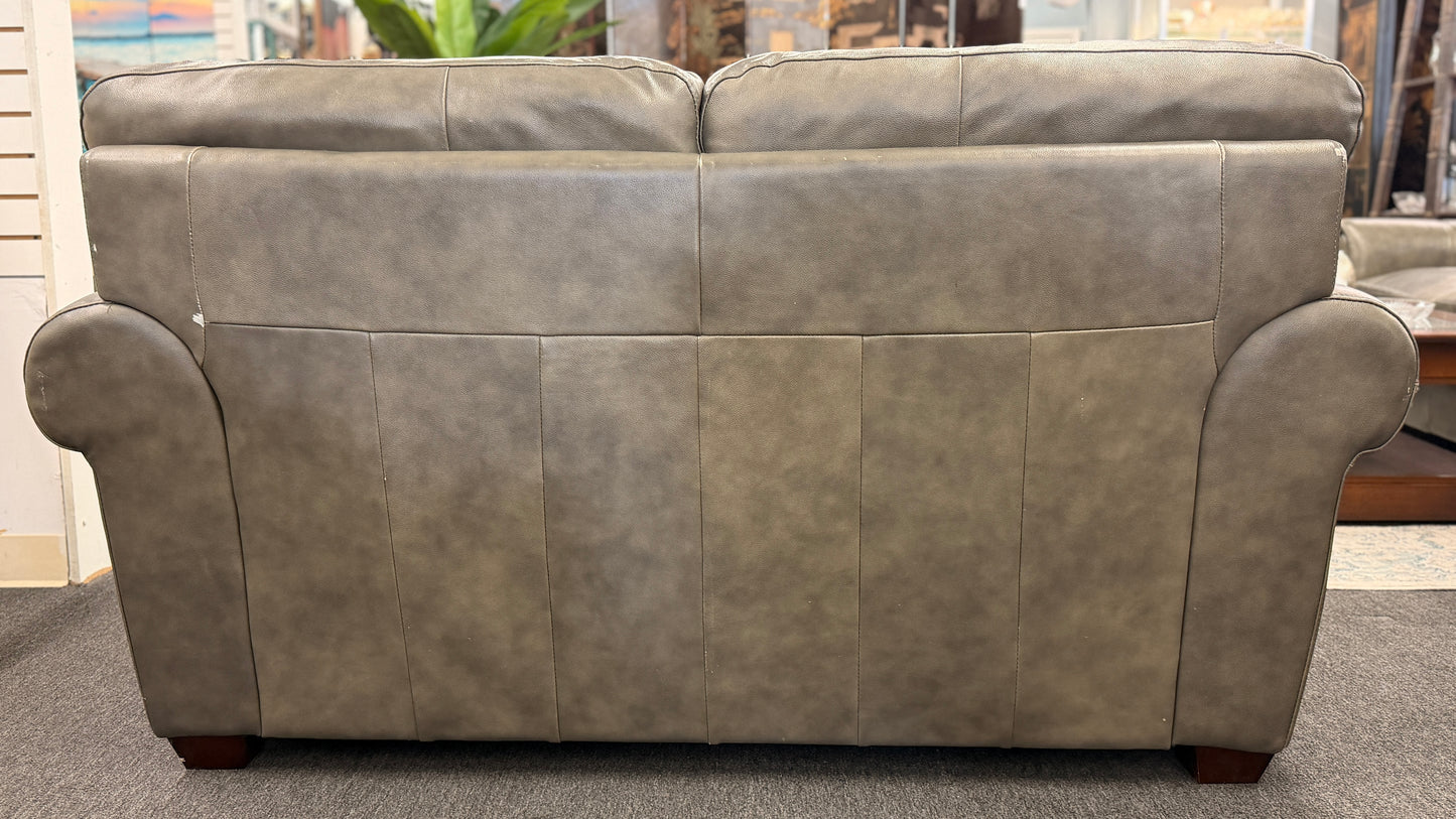 Gray leather sofa in a room with a window and plants.