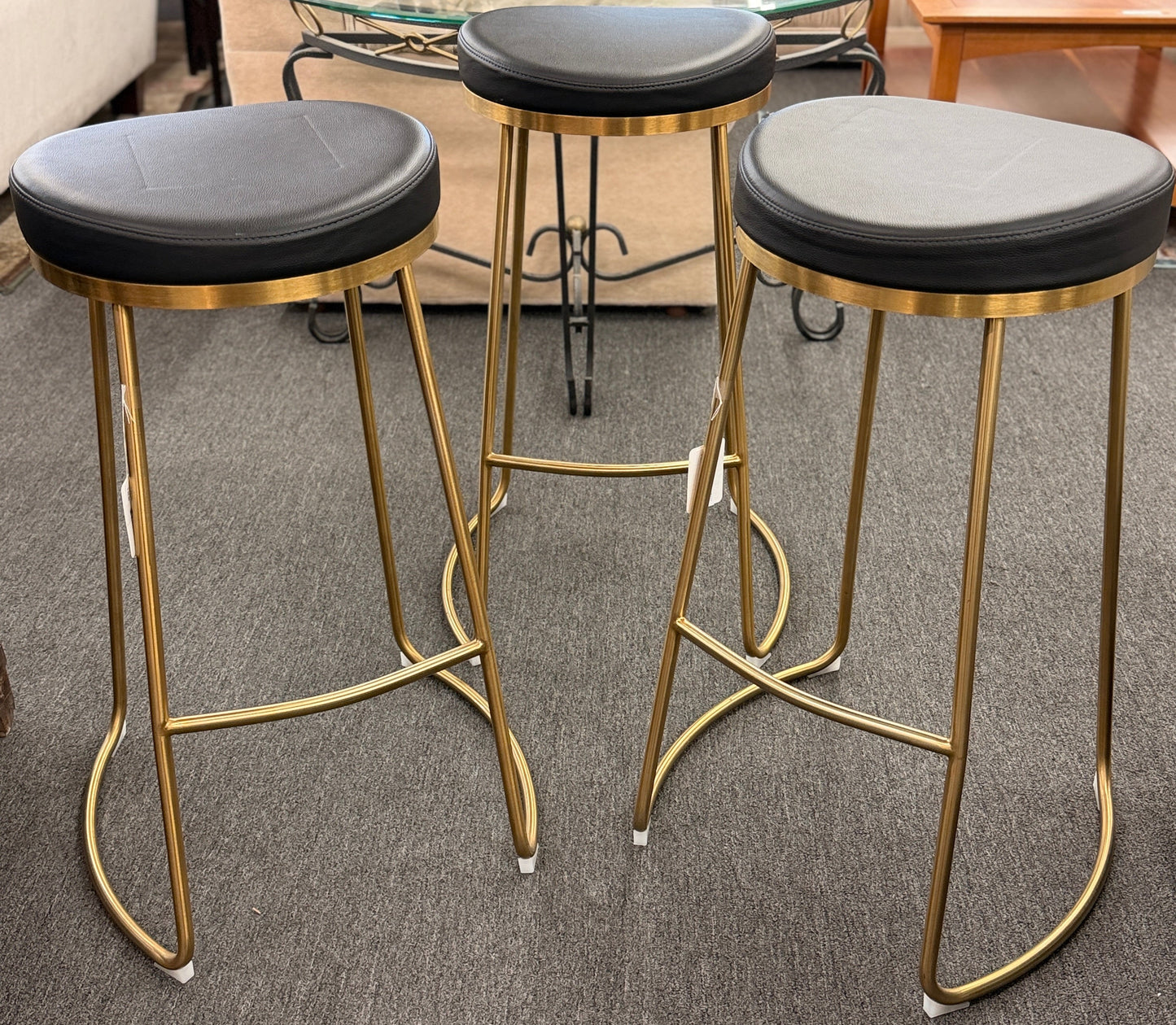 Modern geometric brass and black leather barstool set featuring slender metal legs and a half circle footrest at 2nd Debut Houston consignment showroom