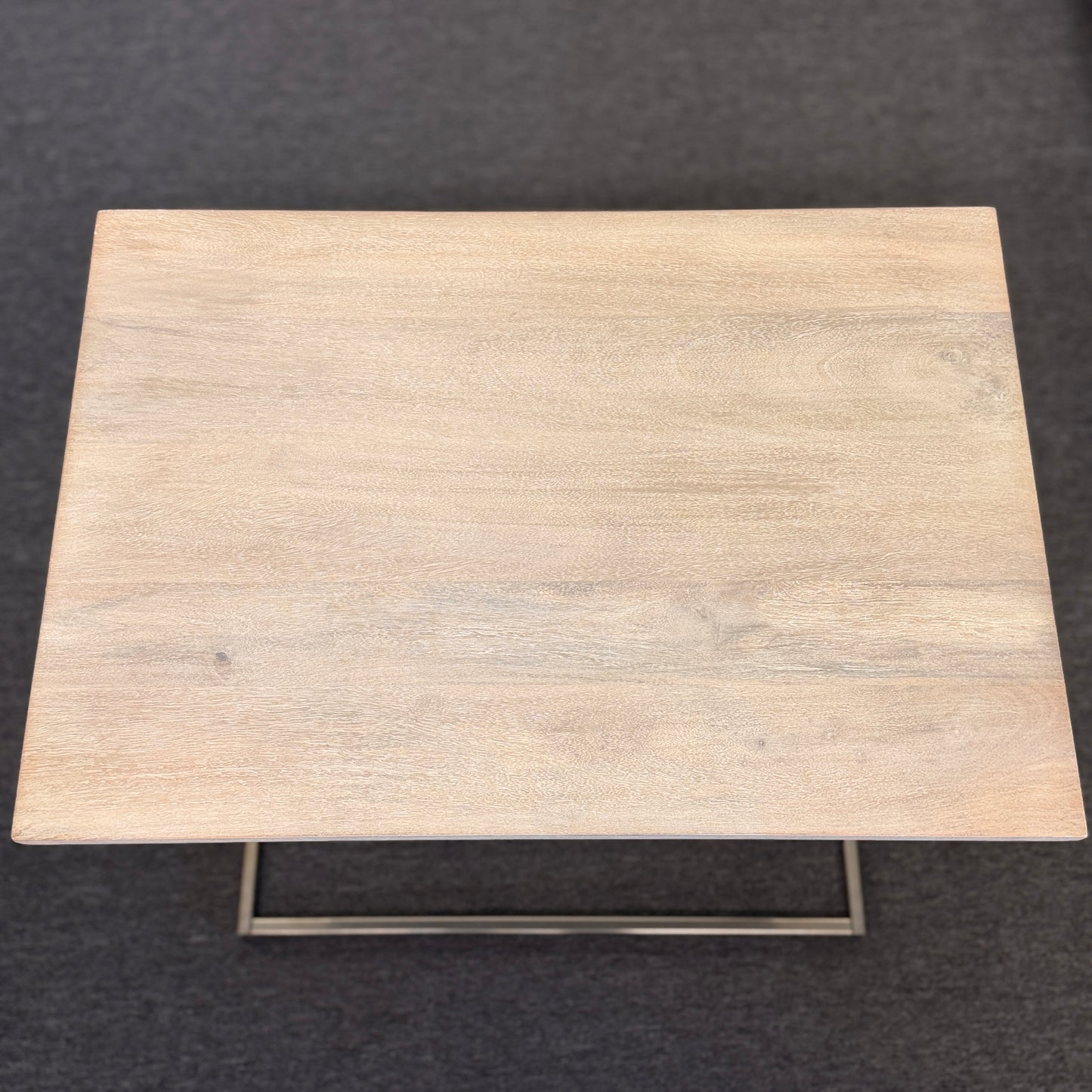 A minimalist C-shaped end table with a wooden tabletop and a slender black metal frame designed to slide over a sofa arm.