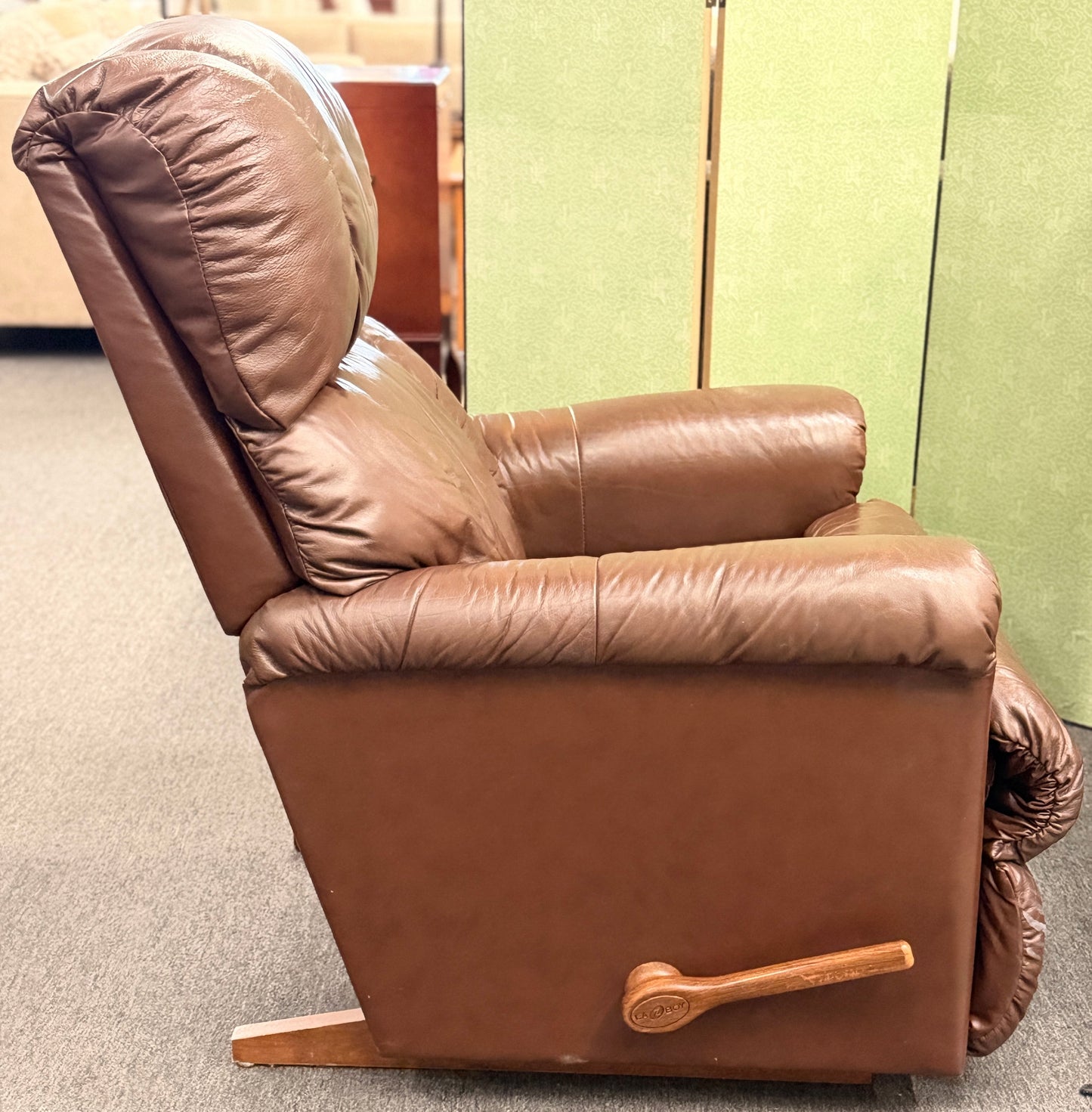 A plush, overstuffed brown leather recliner chair with thick pillowy back cushions and traditional rolled arms.