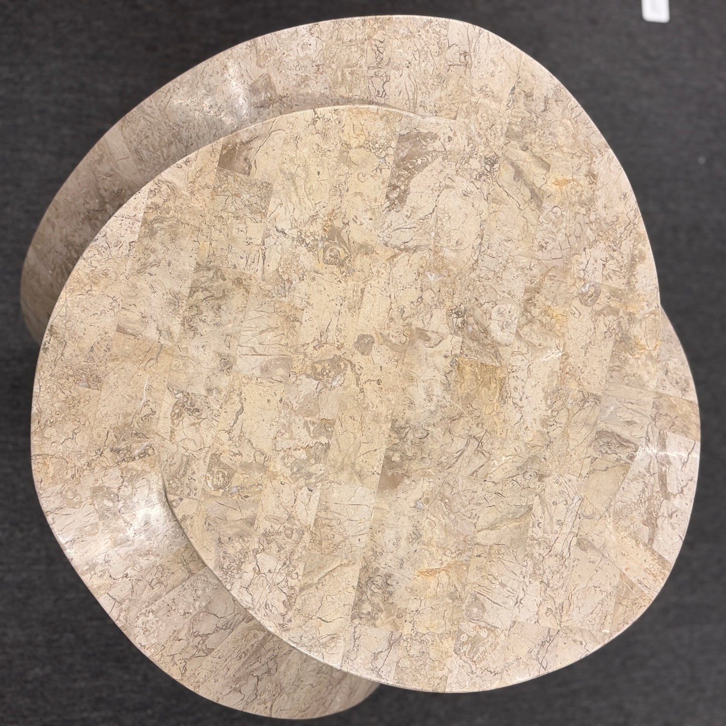 Tessellated stone end table featuring a polished light-colored stone mosaic, organic rounded triangular top, and sculptural curved three-leg base.