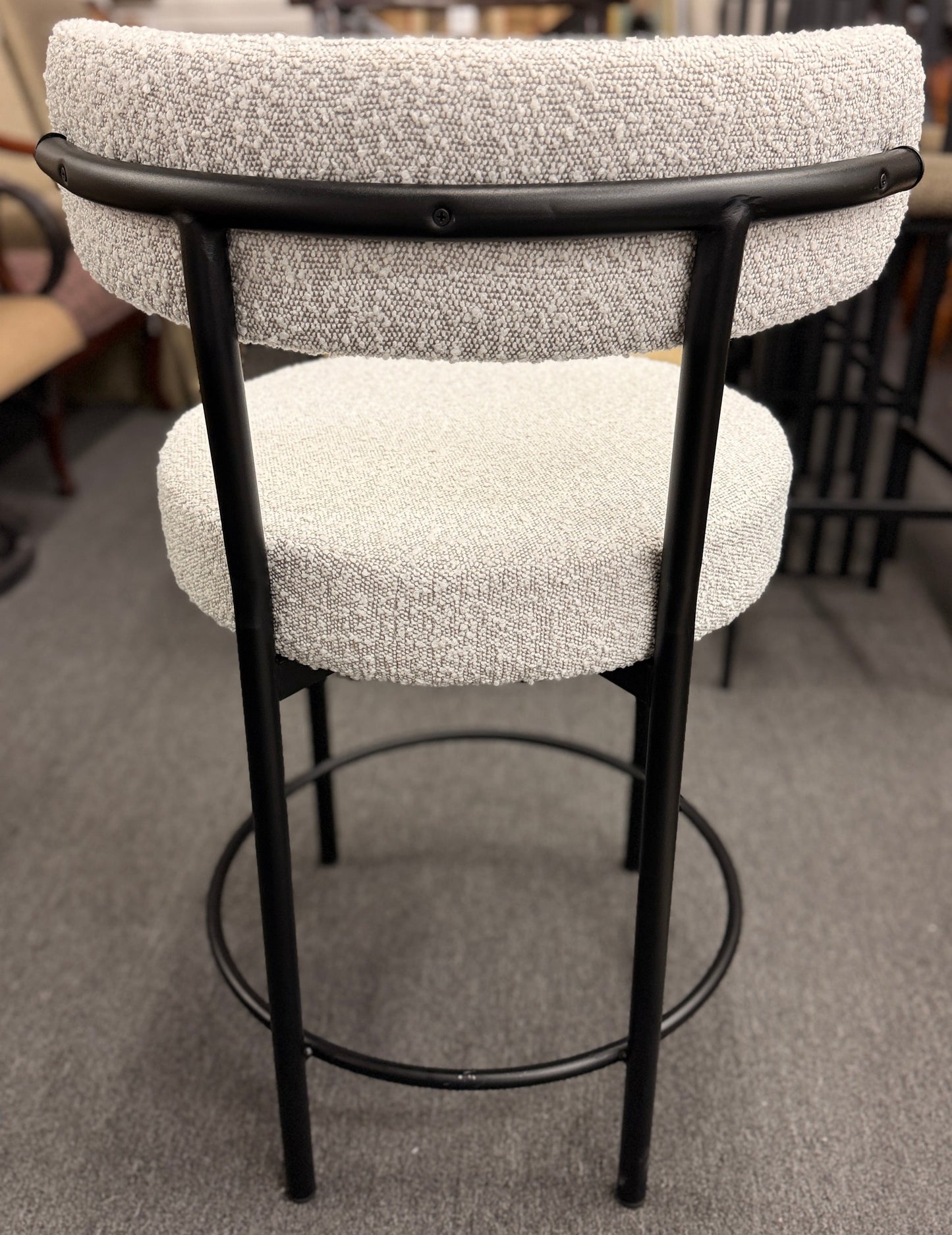 Set of three modern bar stools featuring textured white upholstered seats and curved backrests with sleek black metal frames and built-in footrests.
