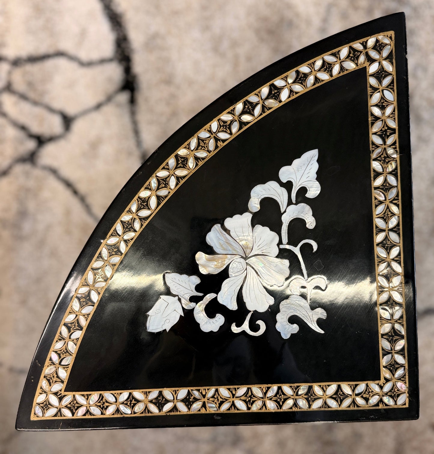 Traditional black lacquer tea table set featuring a round coffee table with a protective glass top, four triangular nesting stools, gold-painted detailing, and mother-of-pearl style floral inlays.