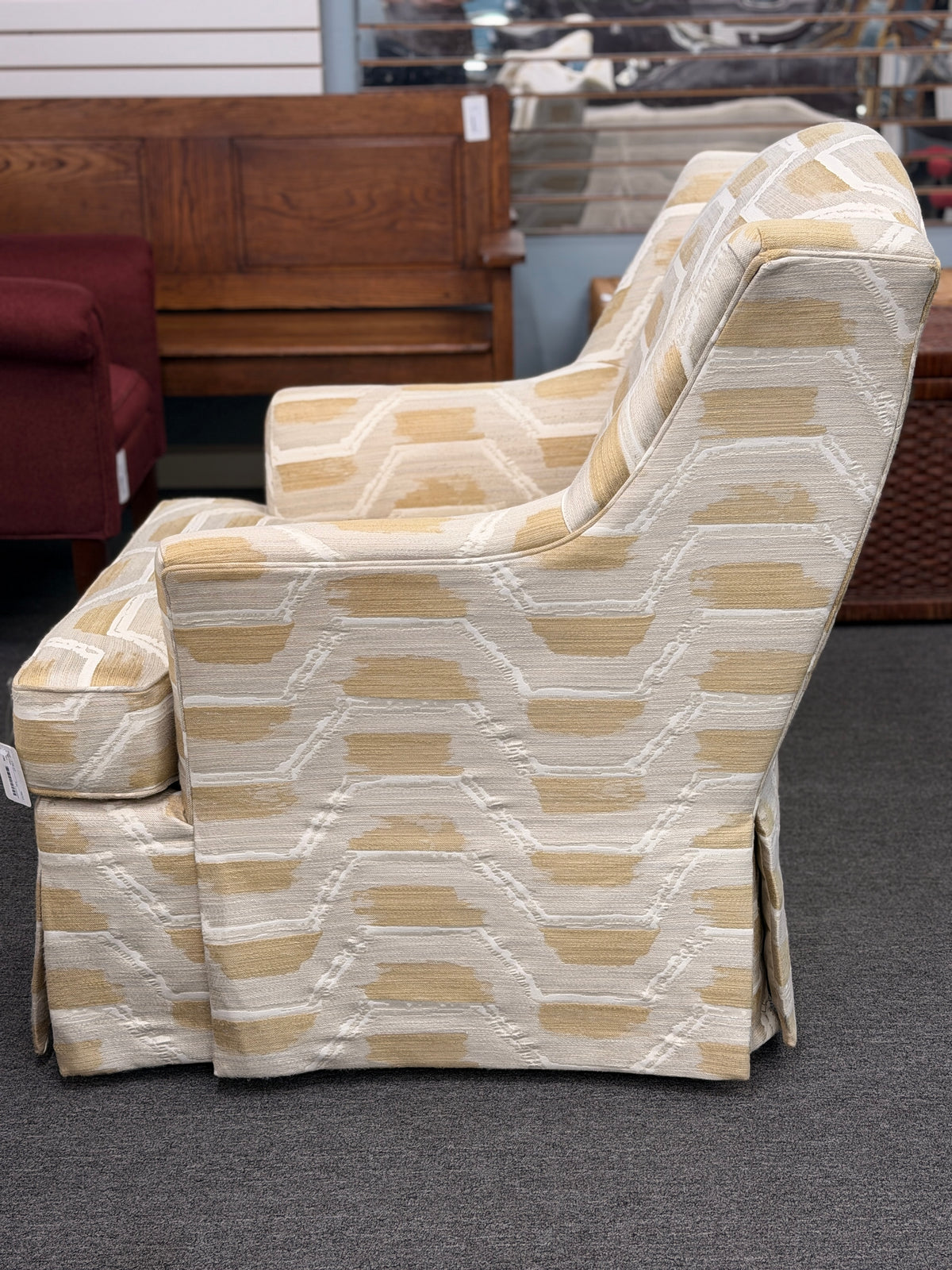 Fully upholstered wingback accent armchair with a tailored skirt featuring an off-white and tan or gold chevron-style geometric pattern in excellent condition.