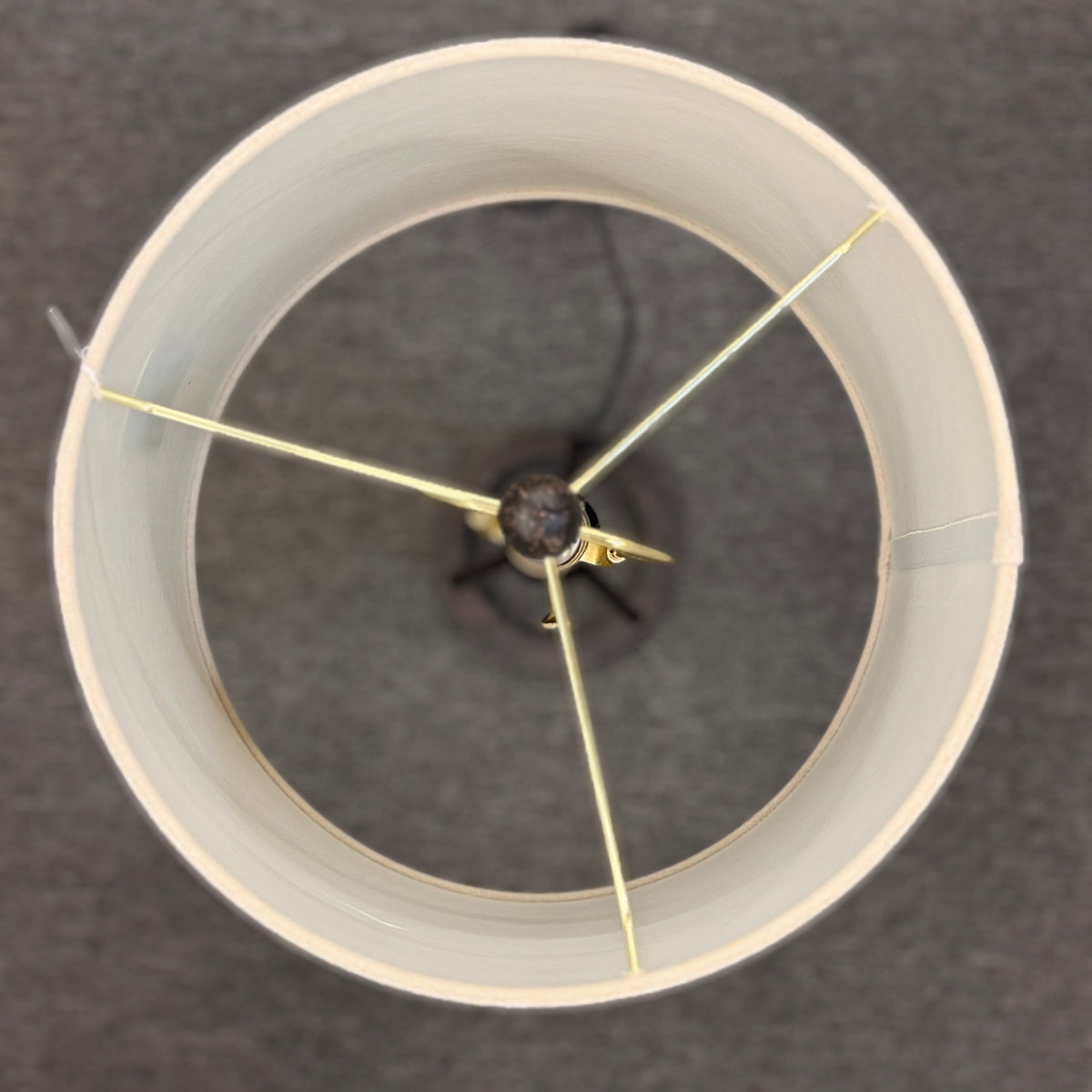 A contemporary minimalist table lamp with a dark bronze or black tripod metal base on a ring stand, topped with an oversized cylindrical off-white linen drum shade in good condition.