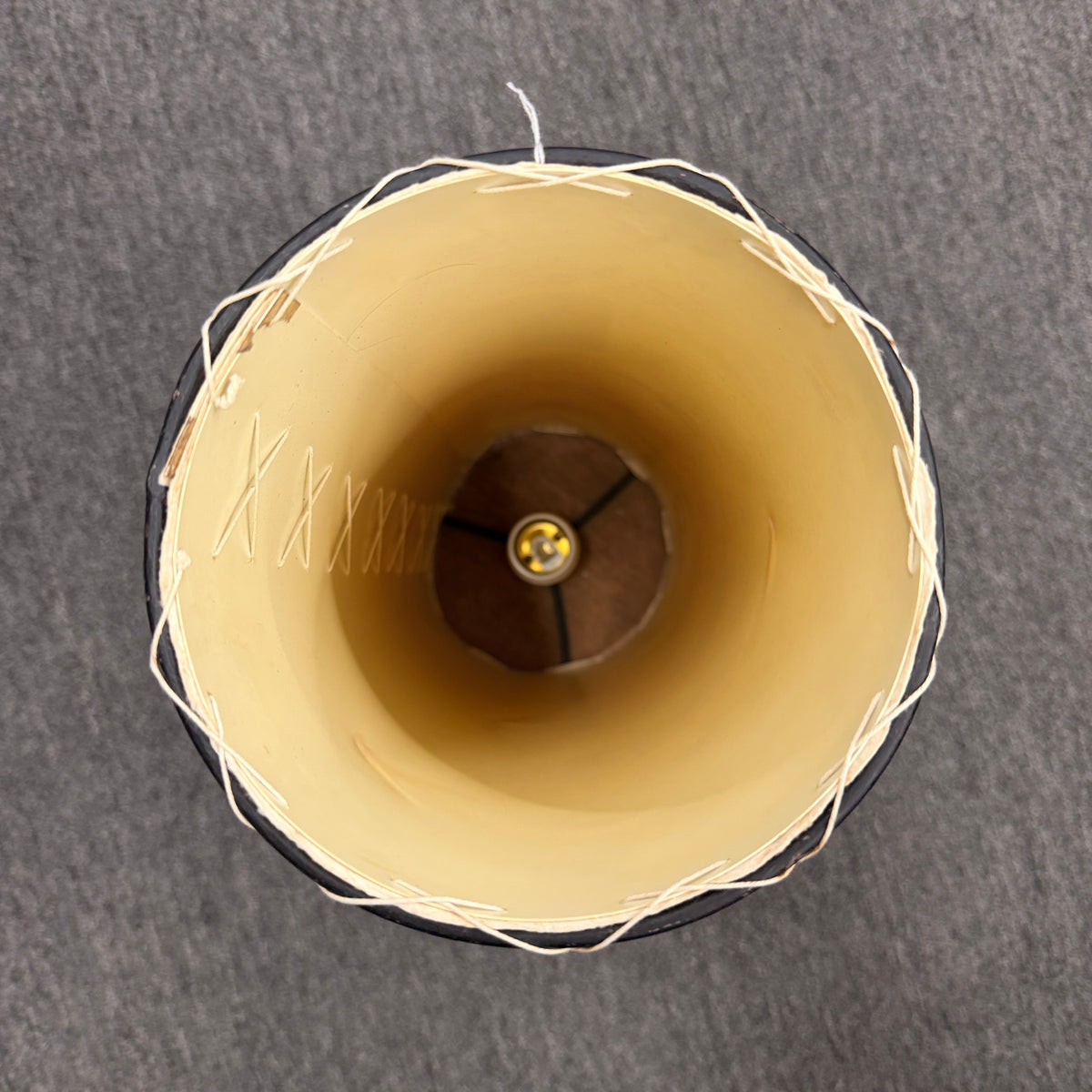 A cylindrical pergamino lamp featuring a textured parchment-style shade resting on a small dark wooden base in excellent condition.