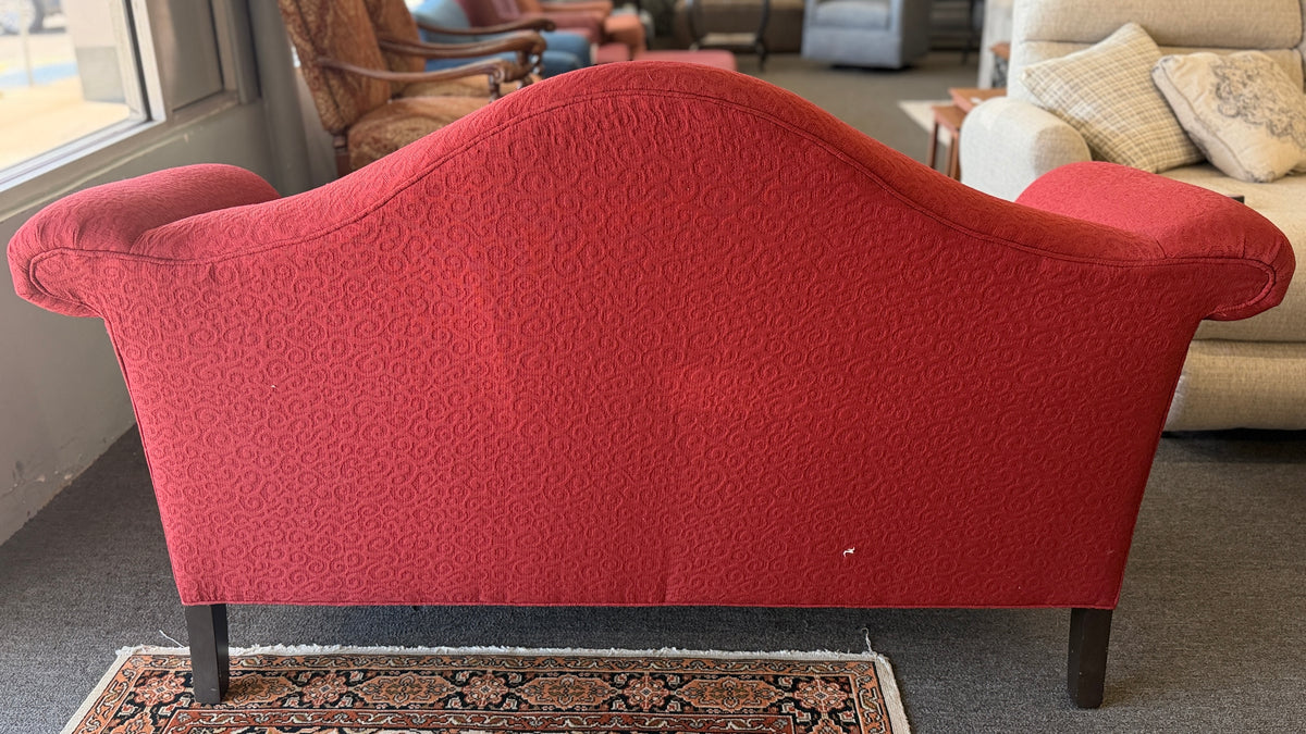 A bright red upholstered Ethan Allen loveseat with a subtly patterned fabric, curved backrest, and dark tapered legs in good condition.