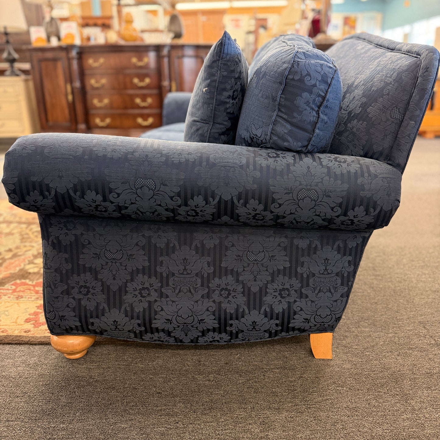 Traditional Ethan Allen three-seater sofa upholstered in blue tone-on-tone damask fabric with English rolled arms, three seat cushions, three back cushions, two matching accent pillows, and turned wooden bun feet.