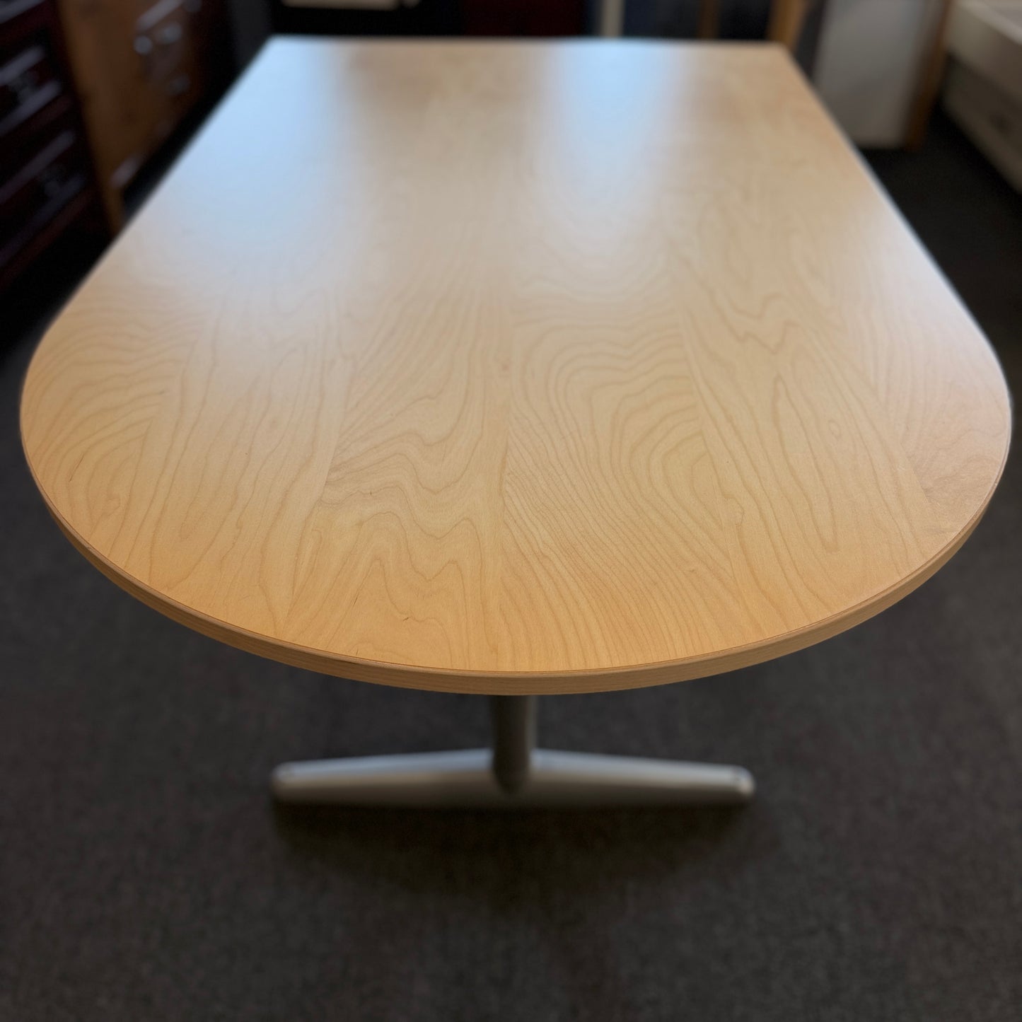 Modern office desk with a light wood D-shaped desktop, angled gray metal legs, and wide stabilizing feet.