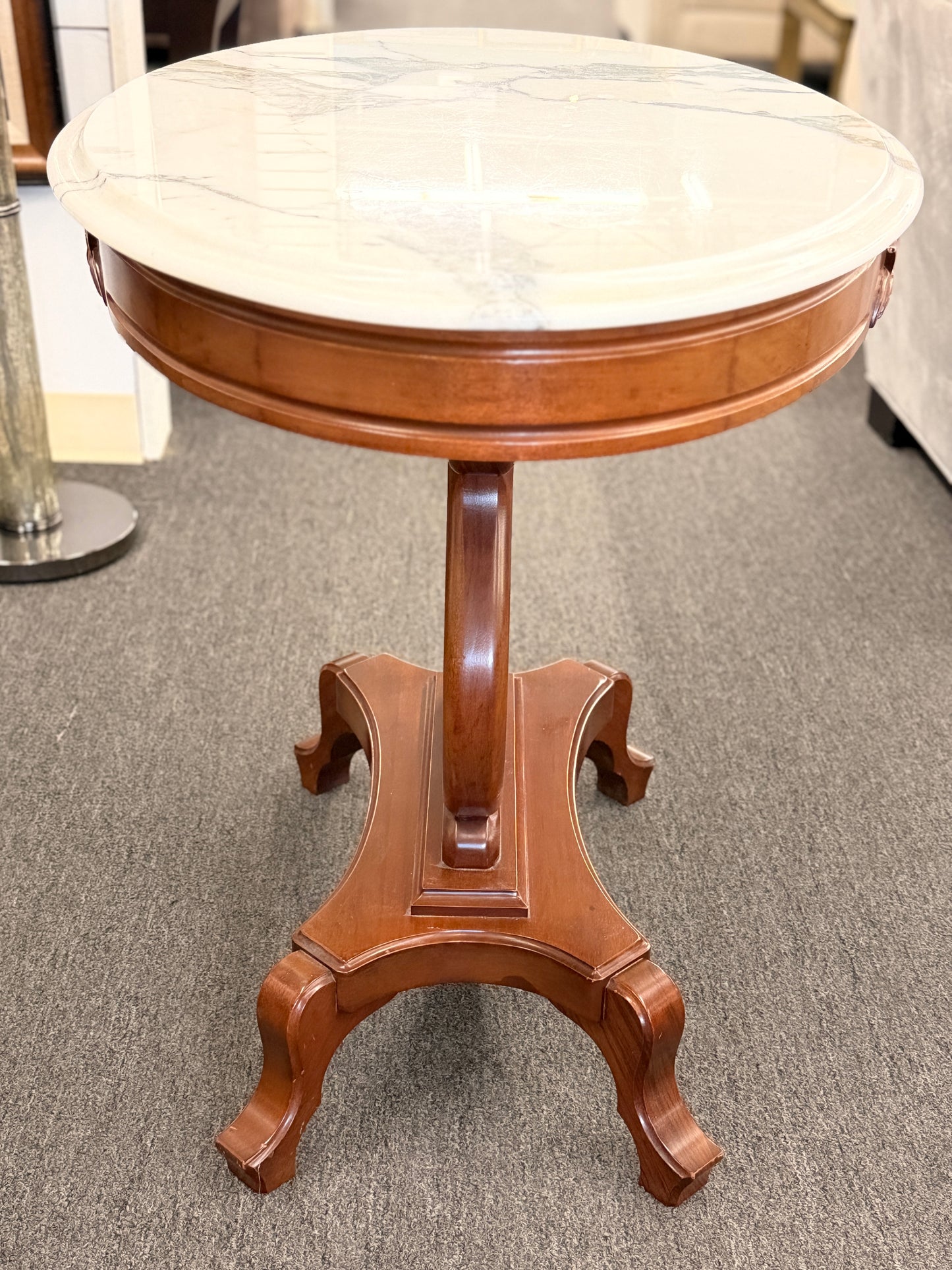 An ornate accent table featuring a white marble top, carved floral apron details, and a traditional lyre-shaped wooden base in excellent condition.