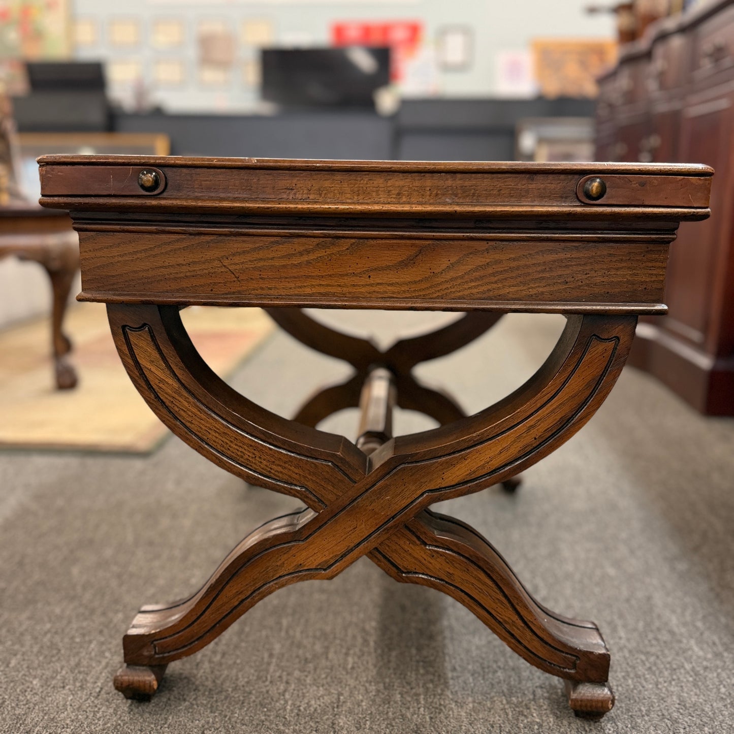 Traditional rectangular wood coffee table featuring a raised-edge tabletop, curved trestle-style legs, and decorative metal nailhead trim along the apron.