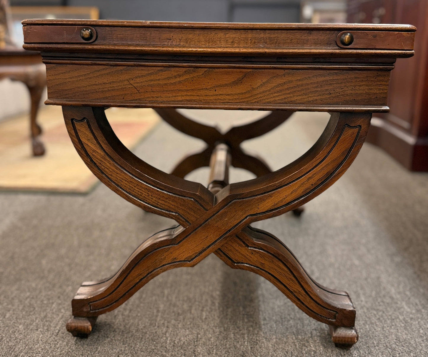 Traditional rectangular wood coffee table featuring a raised-edge tabletop, curved trestle-style legs, and decorative metal nailhead trim along the apron.