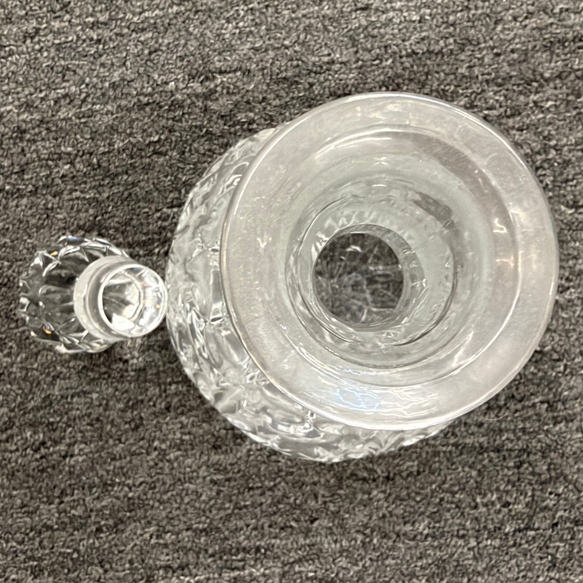 A vintage-style cut-glass decanter with crosshatch and leaf cut patterns, a tall fluted neck, and a matching faceted stopper in excellent condition.