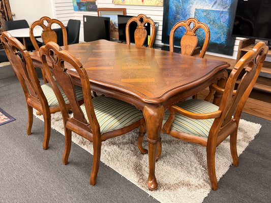 A 7-piece formal dining set featuring a marquetry wood inlay rectangular table with cabriole legs and six carved chairs with striped seats.
