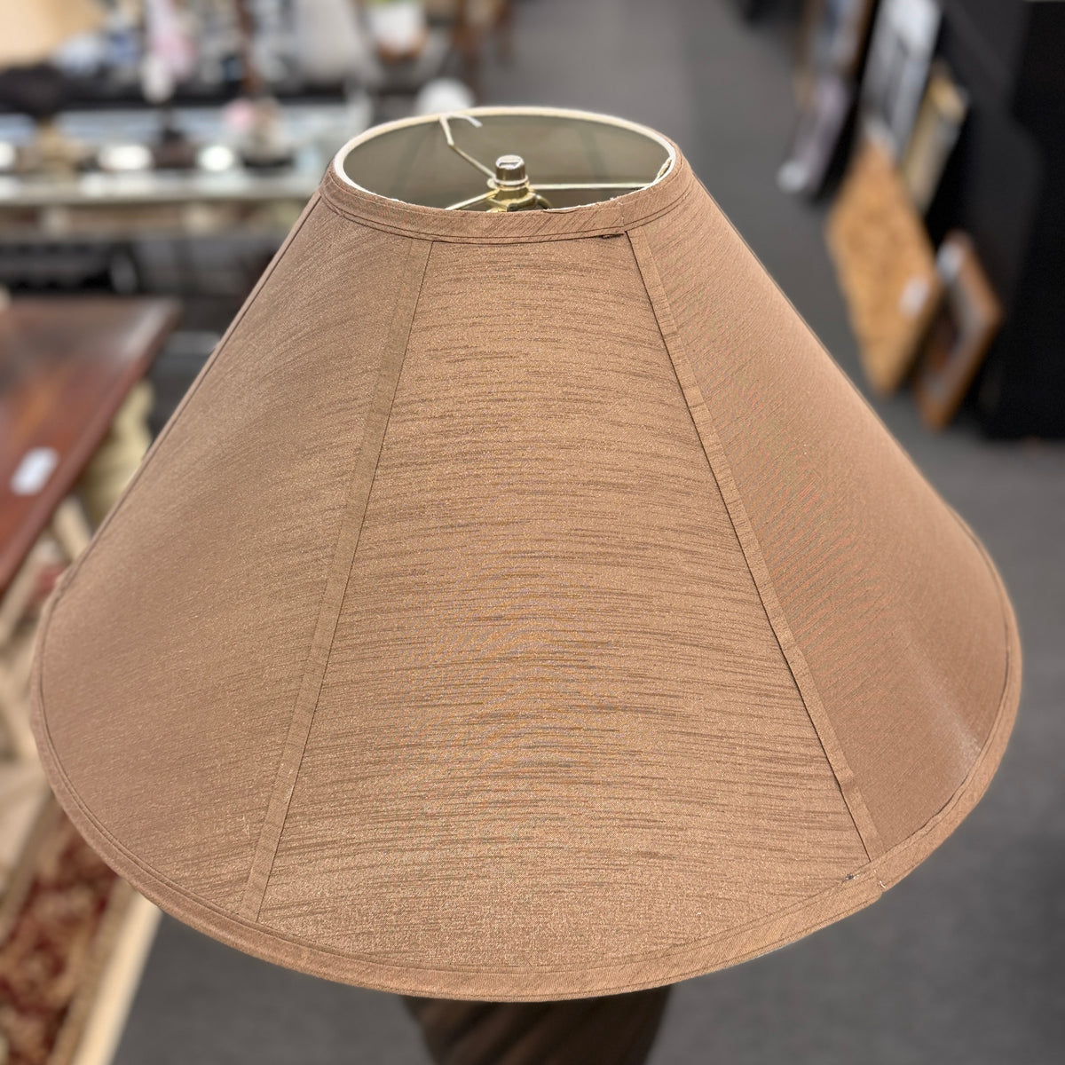 A tall floor lamp featuring a dark twisted pedestal base and a wide tan-colored fabric shade in excellent condition.