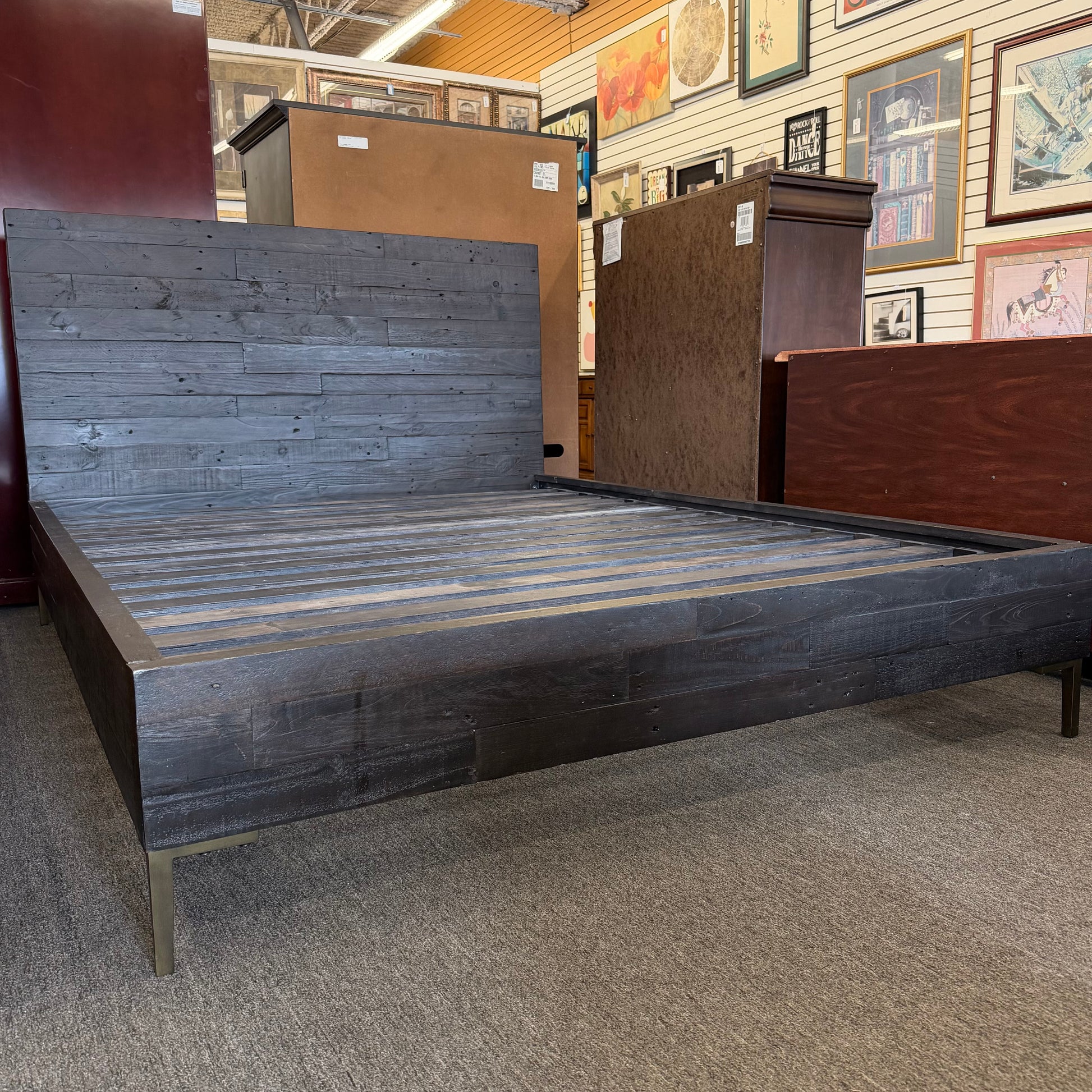 Wooden bed frames on display in a store with framed pictures on the wall.