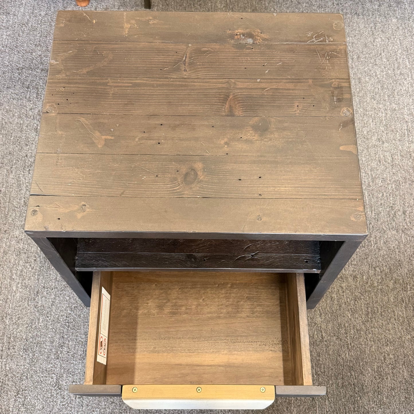 Wooden side table with a drawer open on a textured surface