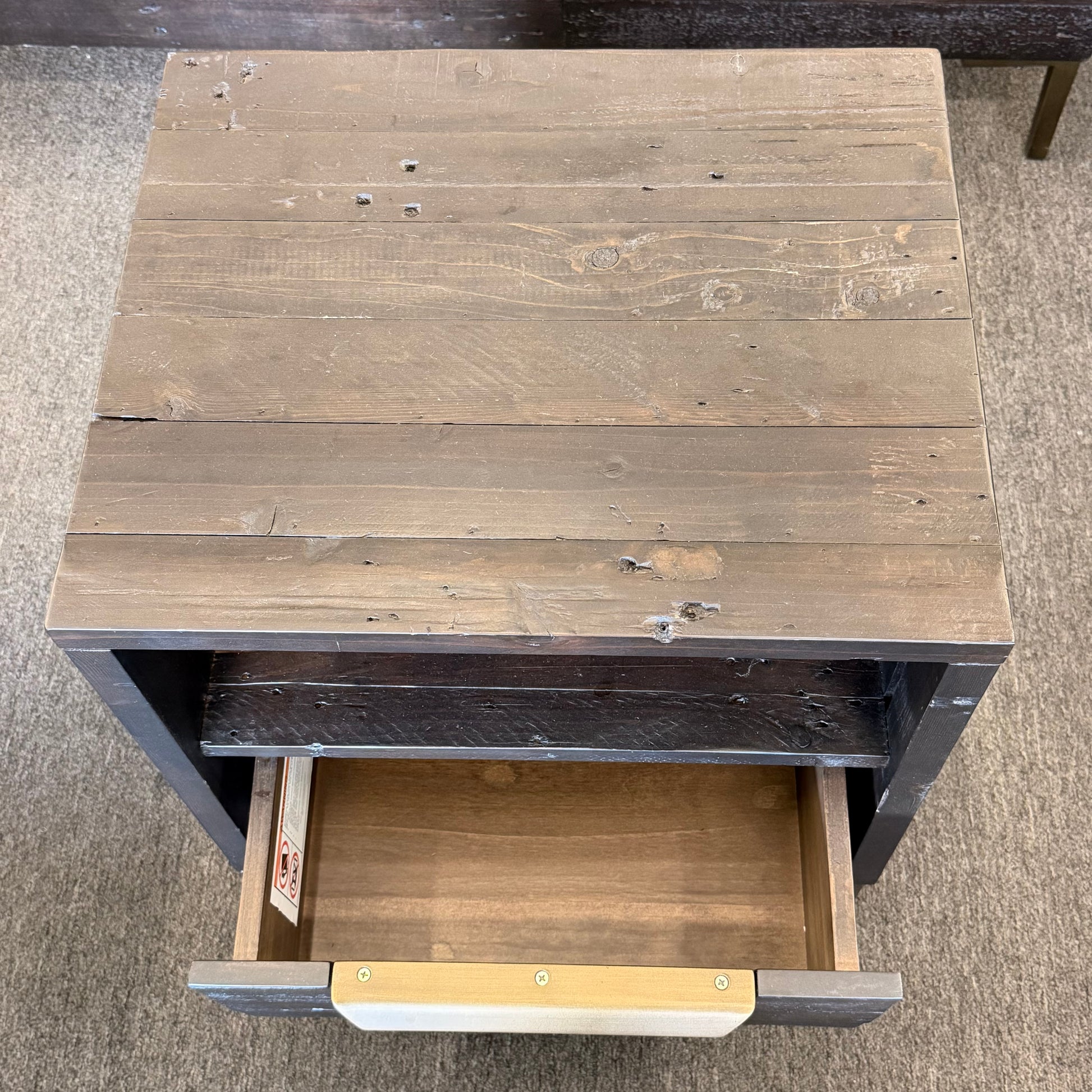 Wooden side table with a drawer open on a carpeted floor