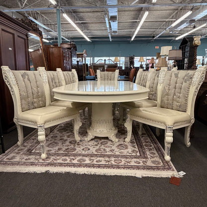Dining room set with round table and upholstered chairs in a showroom setting.
