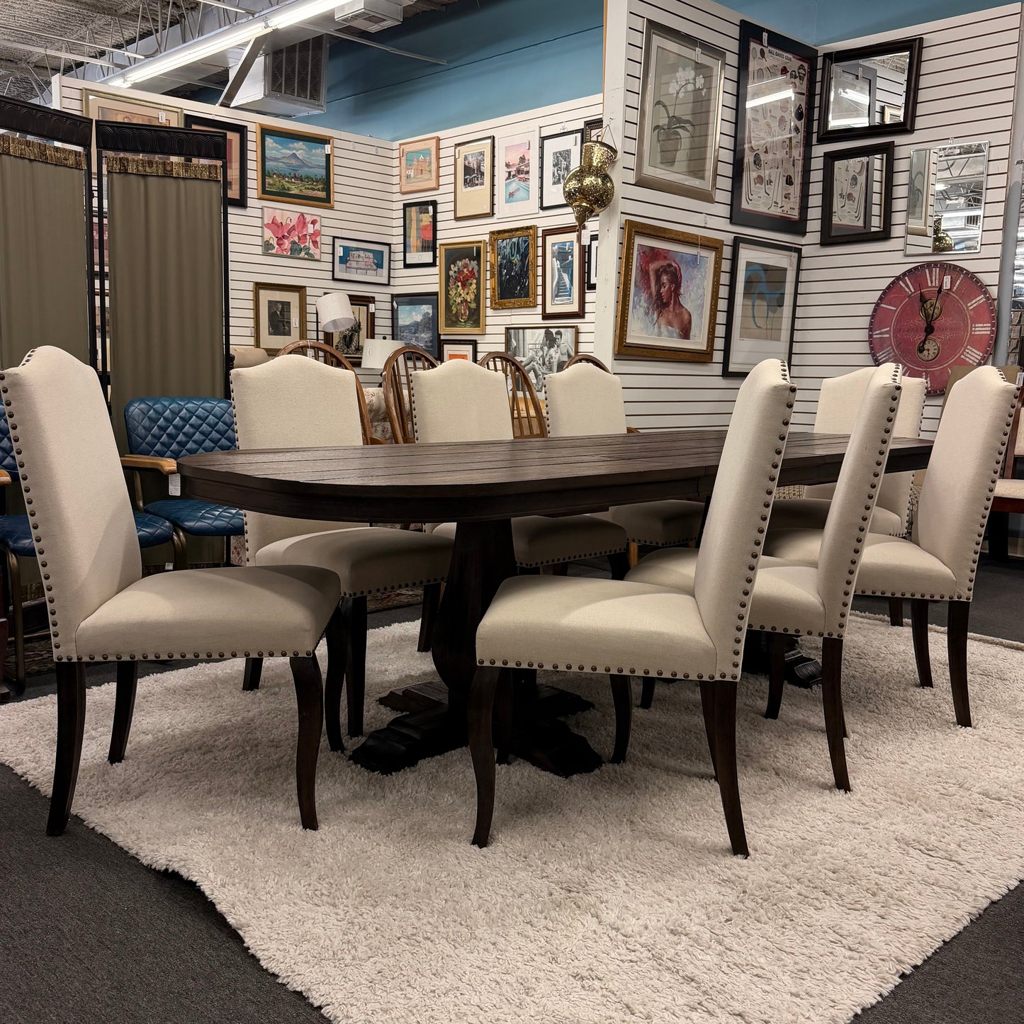 Dining room set with a round wooden table and beige chairs in a showroom setting.
