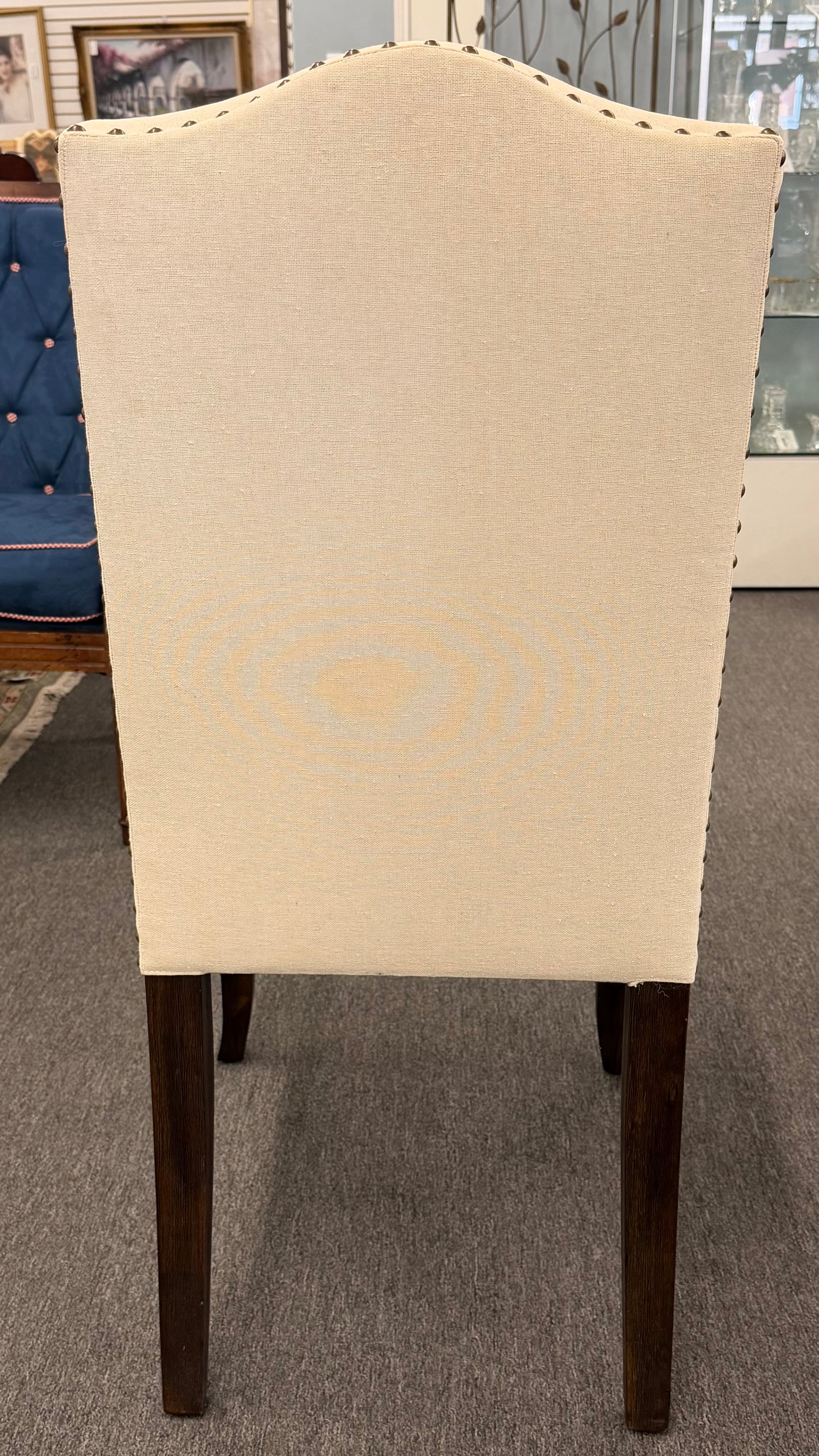 Beige upholstered chair with wooden legs on a gray carpet