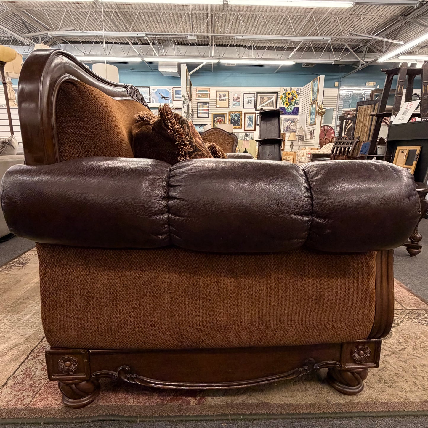 Brown leather sofa in a store setting with various items in the background
