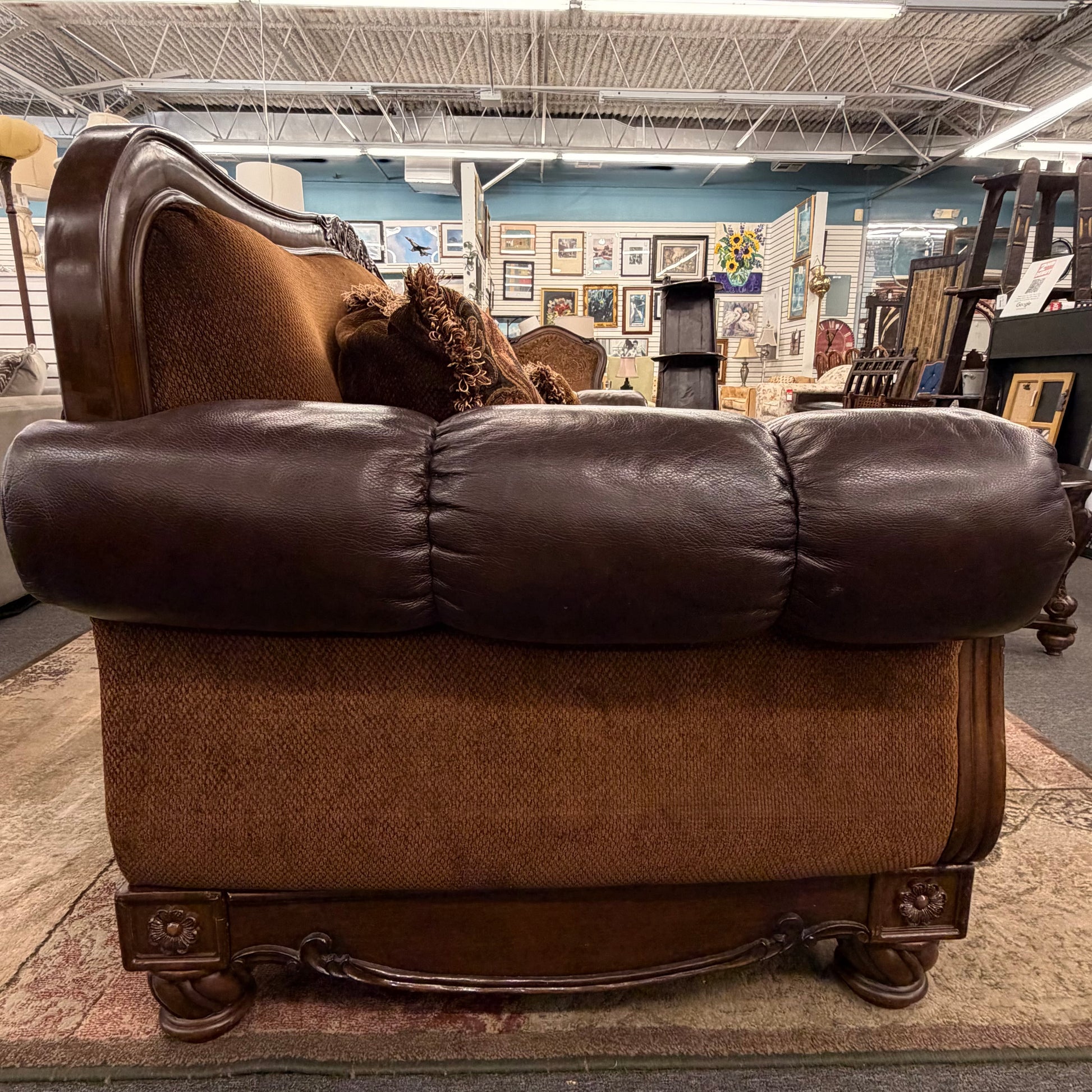 Brown leather sofa in a store setting with various items in the background