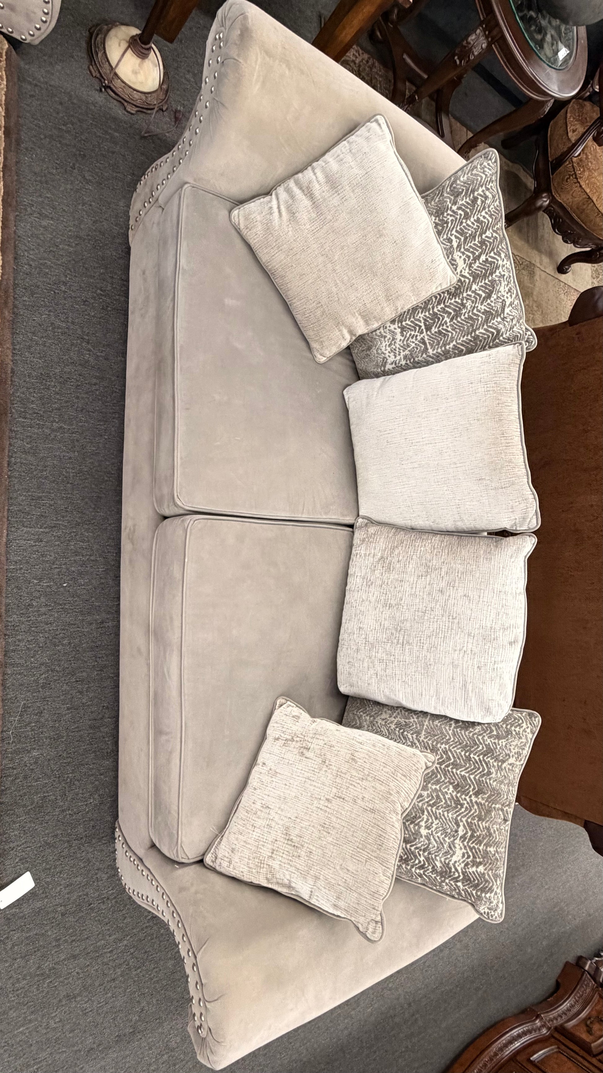 Gray sectional sofa with decorative pillows on a carpeted floor.