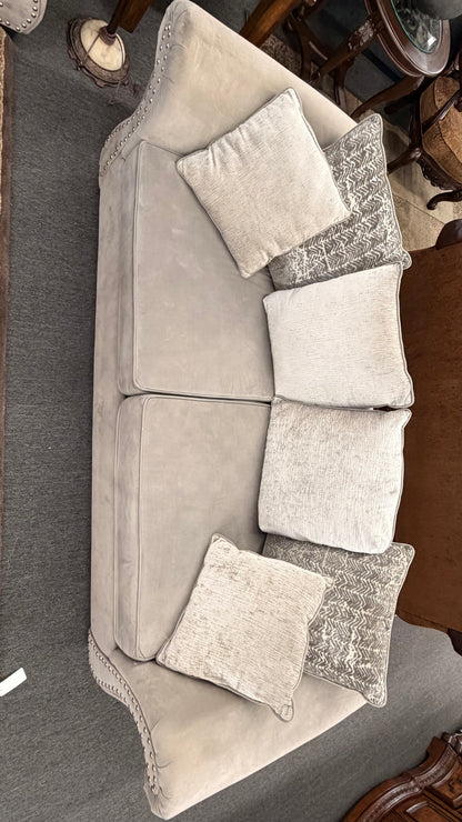 Gray sectional sofa with decorative pillows on a carpeted floor.