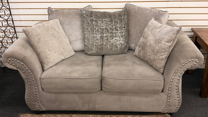 Beige sofa with patterned cushions against a neutral background