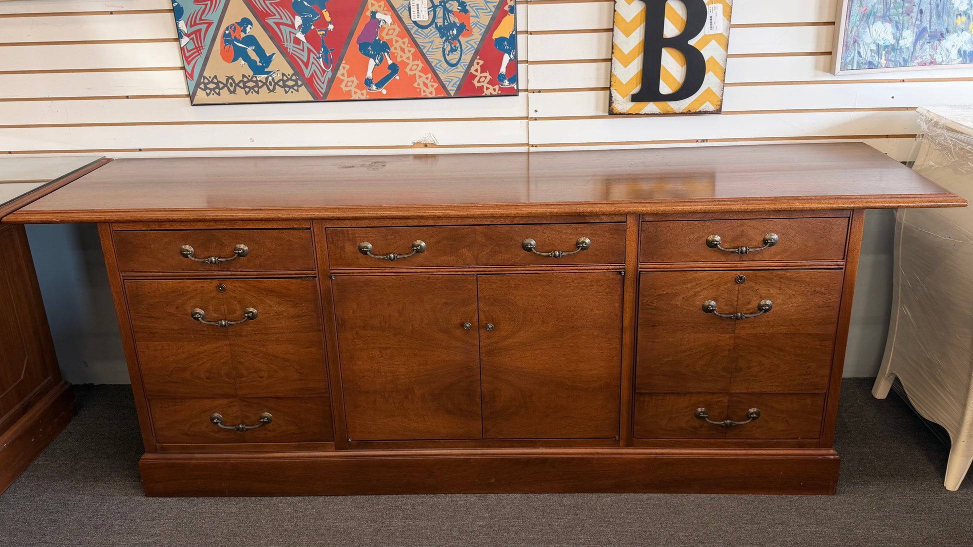 Wooden desk with multiple drawers and a glass top in a room setting.
