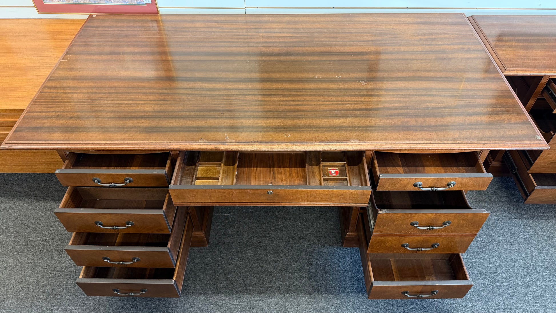 Wooden desk with multiple drawers on a gray floor.