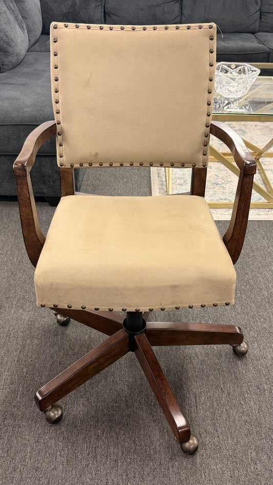 Beige office chair with wooden frame and wheels on a gray floor.