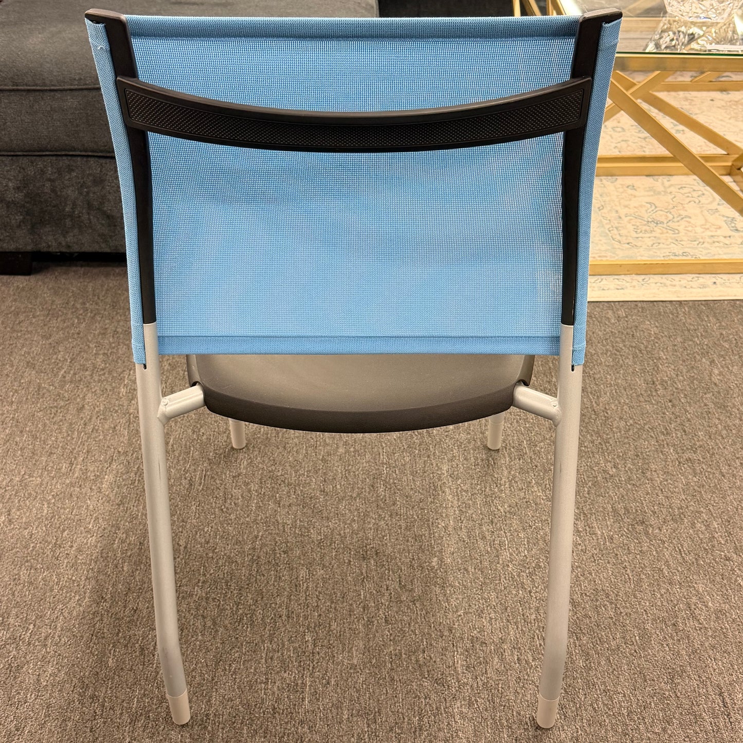 Blue office chair with black mesh backrest on a carpeted floor.