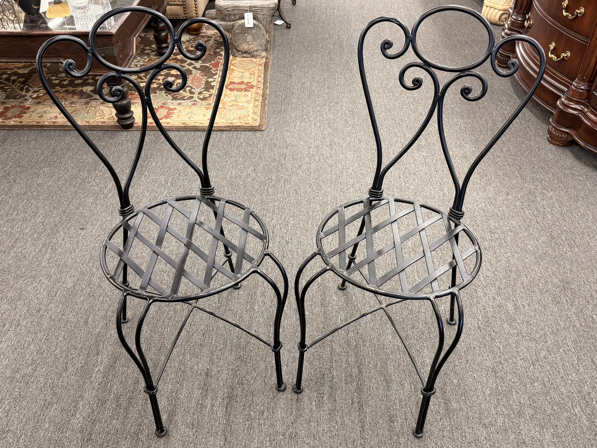 Two ornate metal chairs on a carpeted floor.