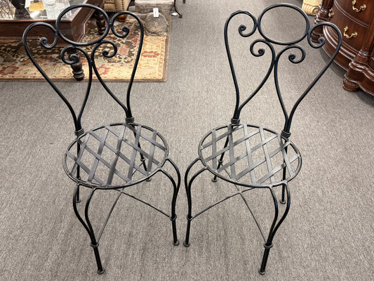 Two ornate metal chairs on a carpeted floor.