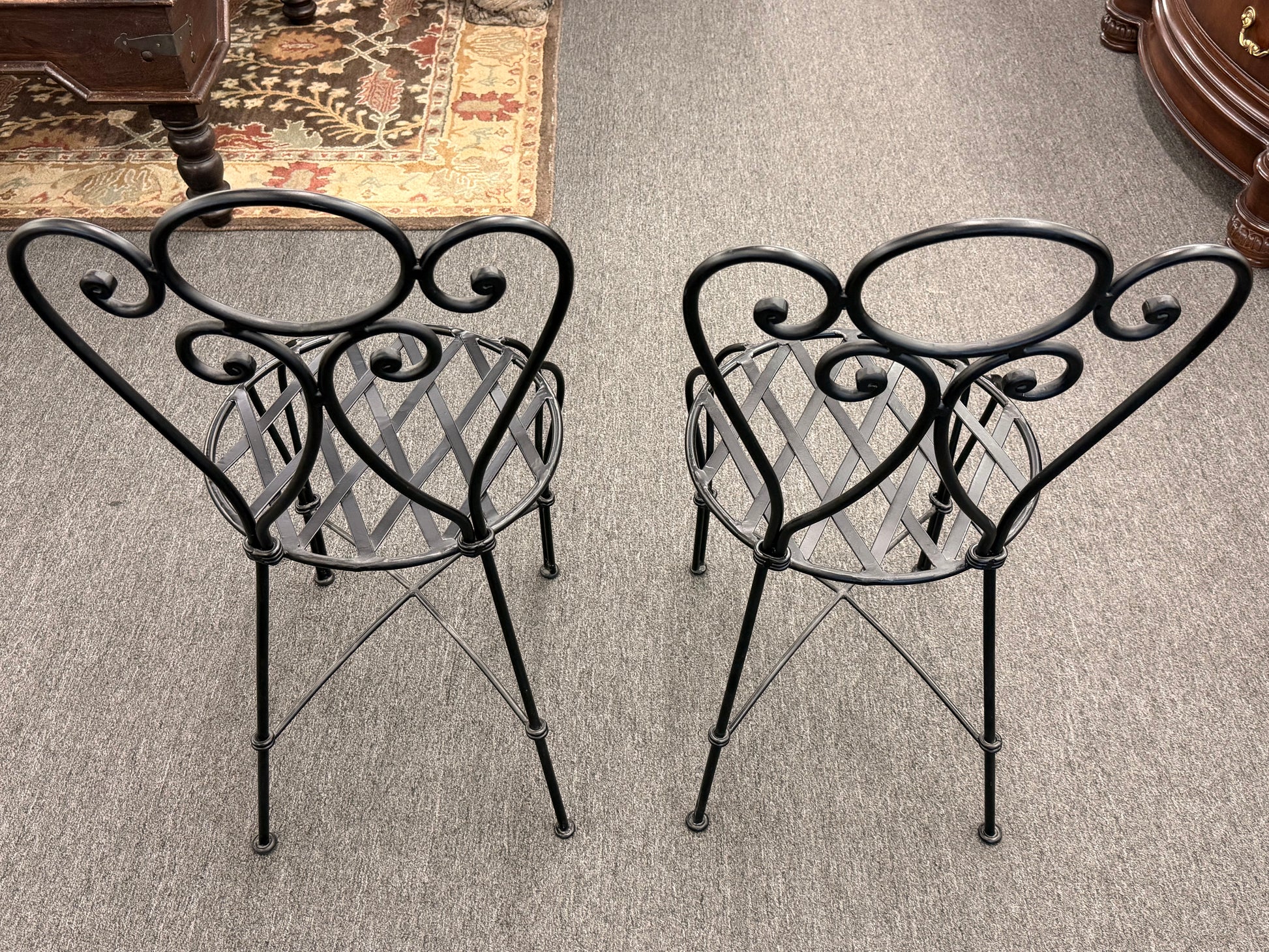Two decorative metal chairs with intricate designs on a carpeted floor.