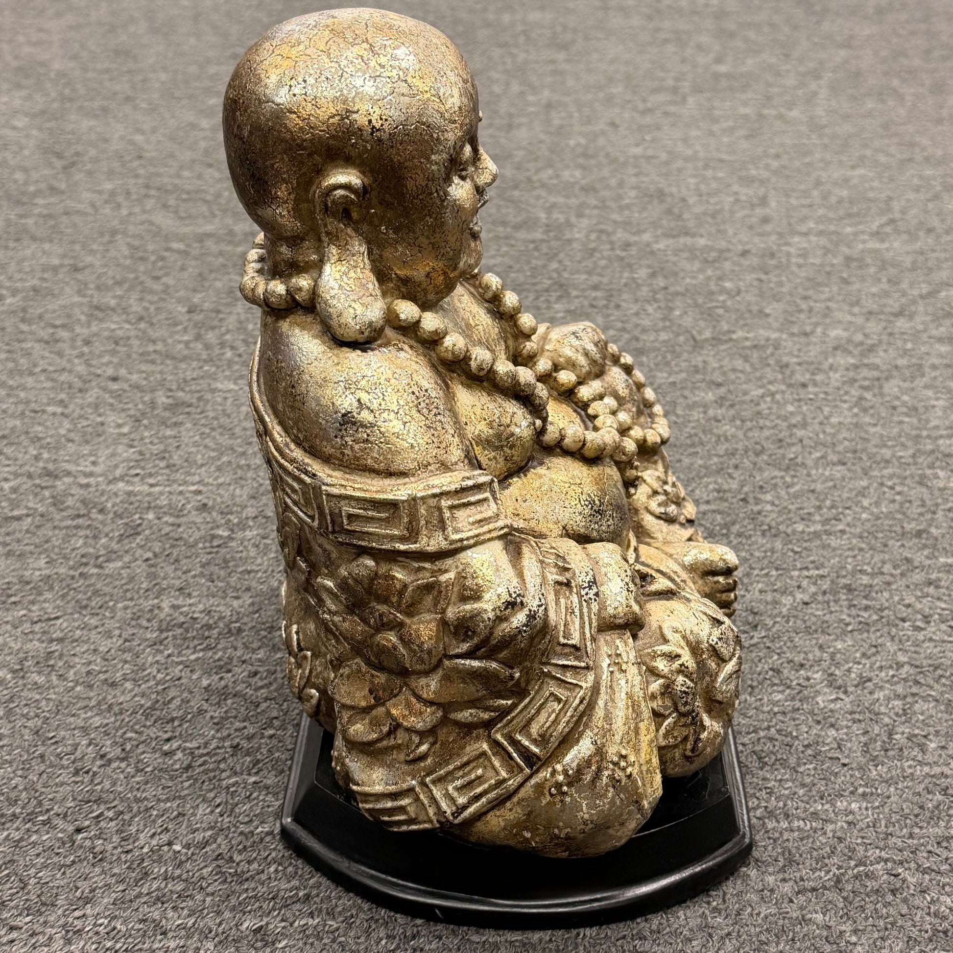 Bronze statue of a seated figure on a gray surface