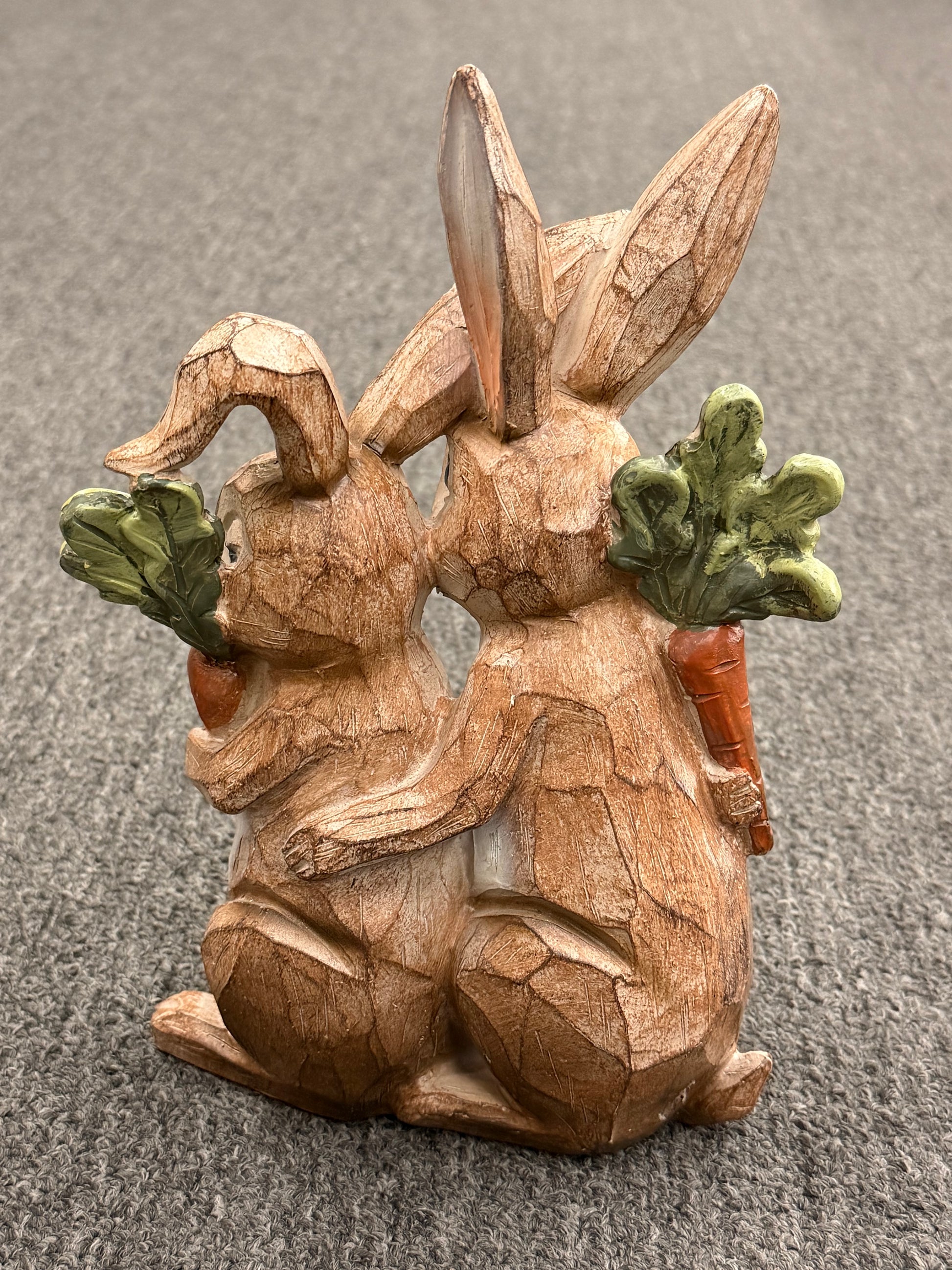 Wooden rabbit figurine with a carrot on a gray surface