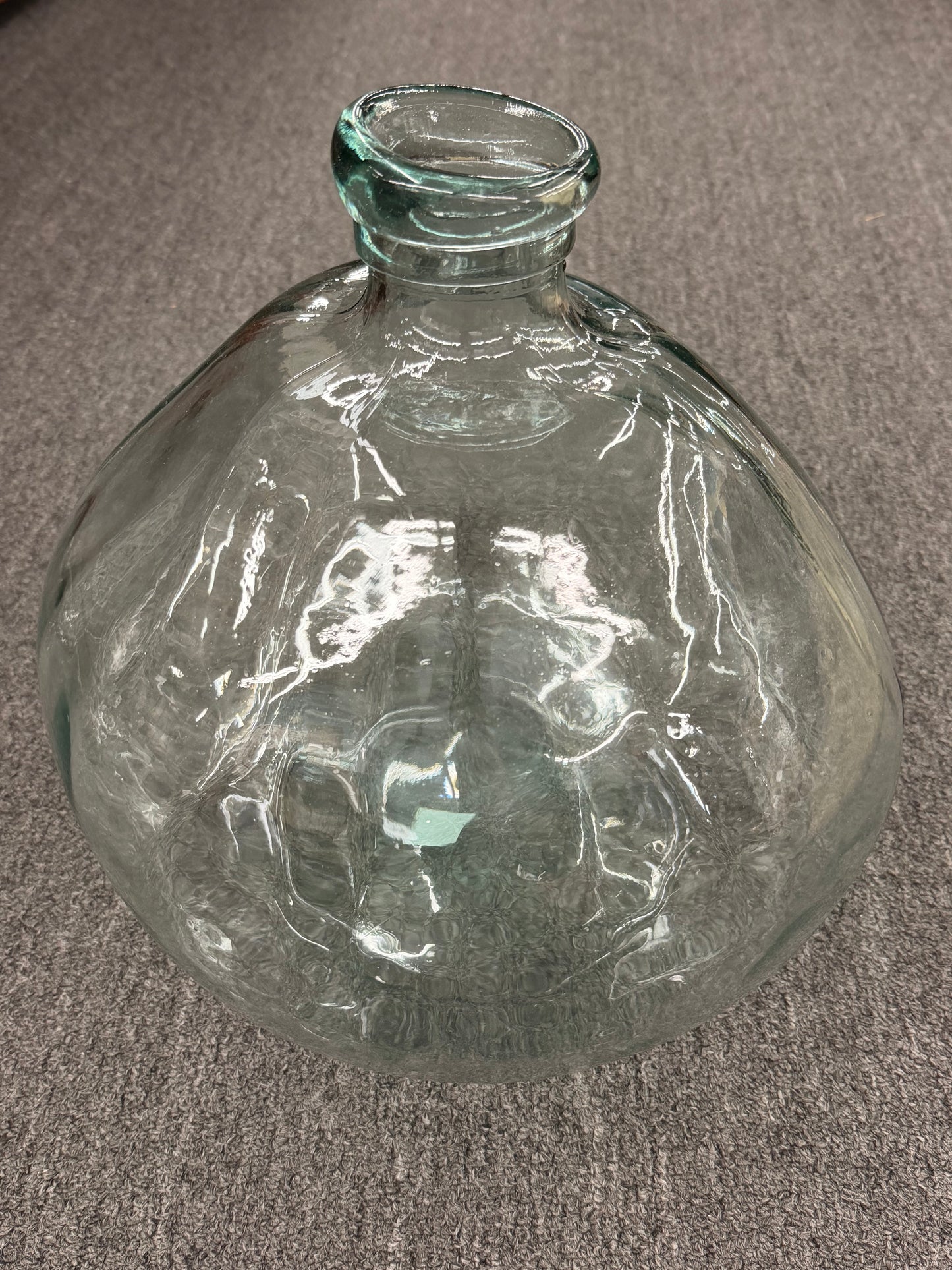 Clear glass bottle on a gray carpeted floor