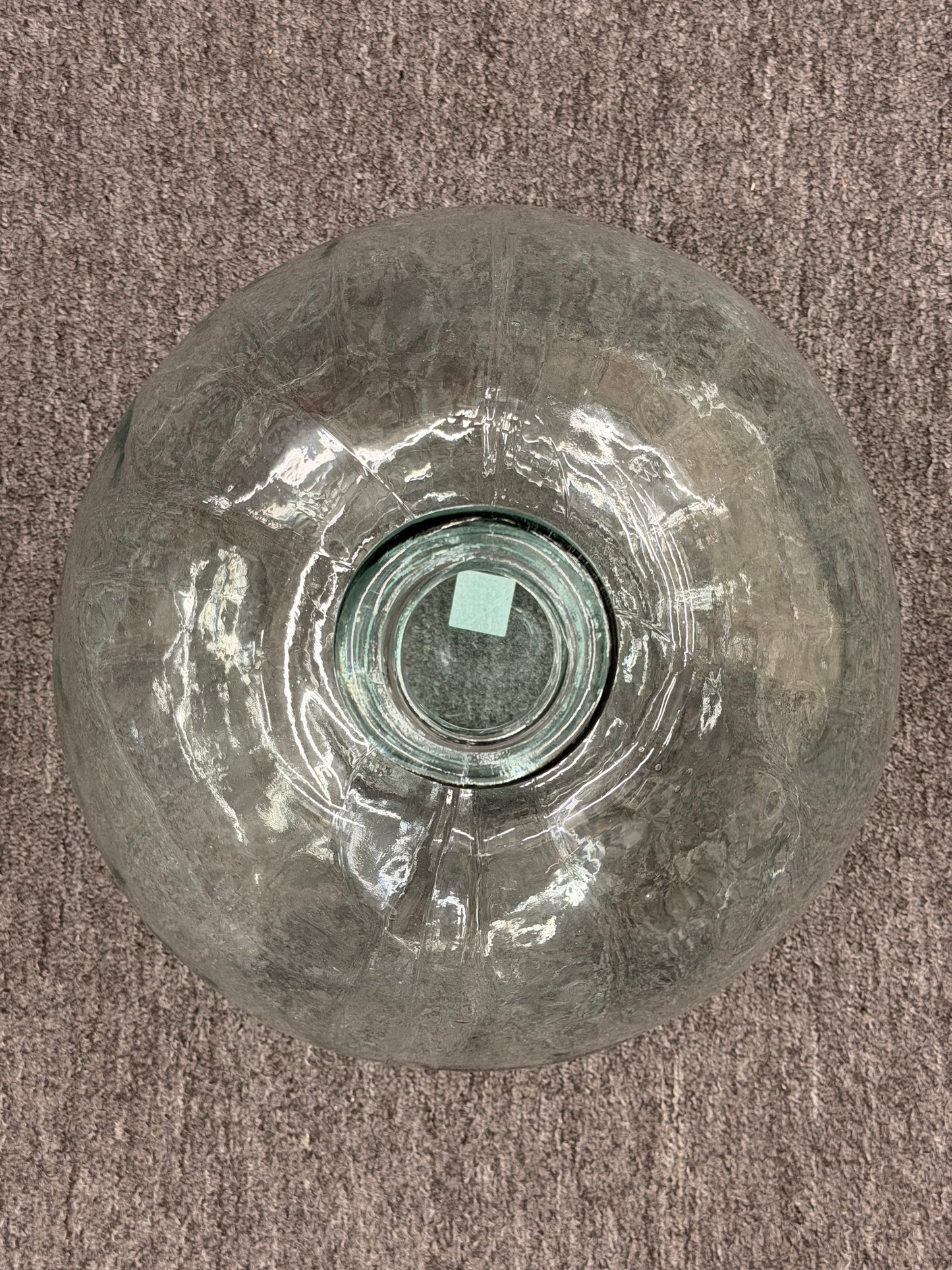 Glass vase with a large crack on a brown carpet