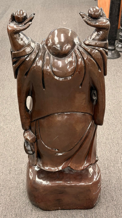 Bronze statue of a figure with outstretched arms on a neutral background