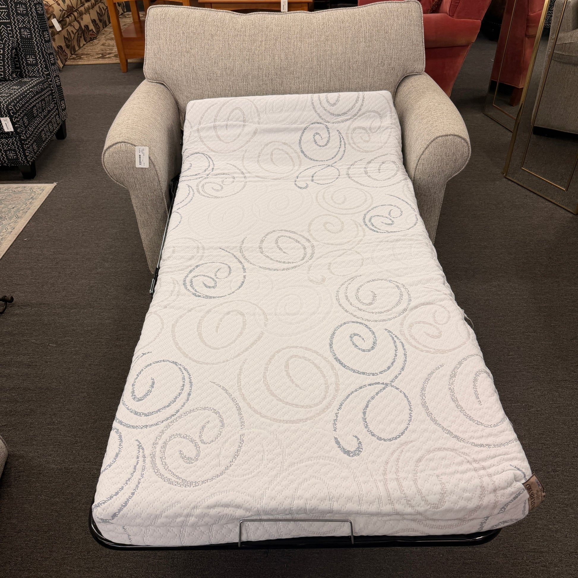 Gray armchair with a white quilted cover featuring circular patterns in a furniture store.
