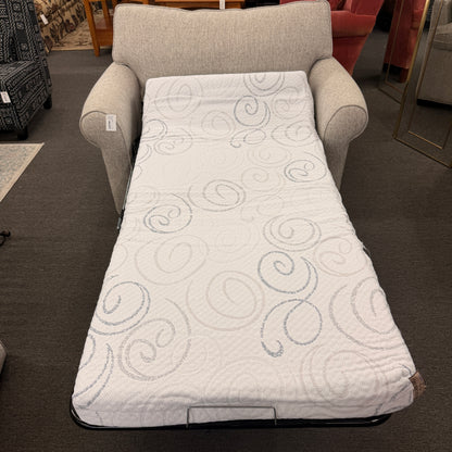 Gray armchair with a white quilted cover featuring circular patterns in a furniture store.