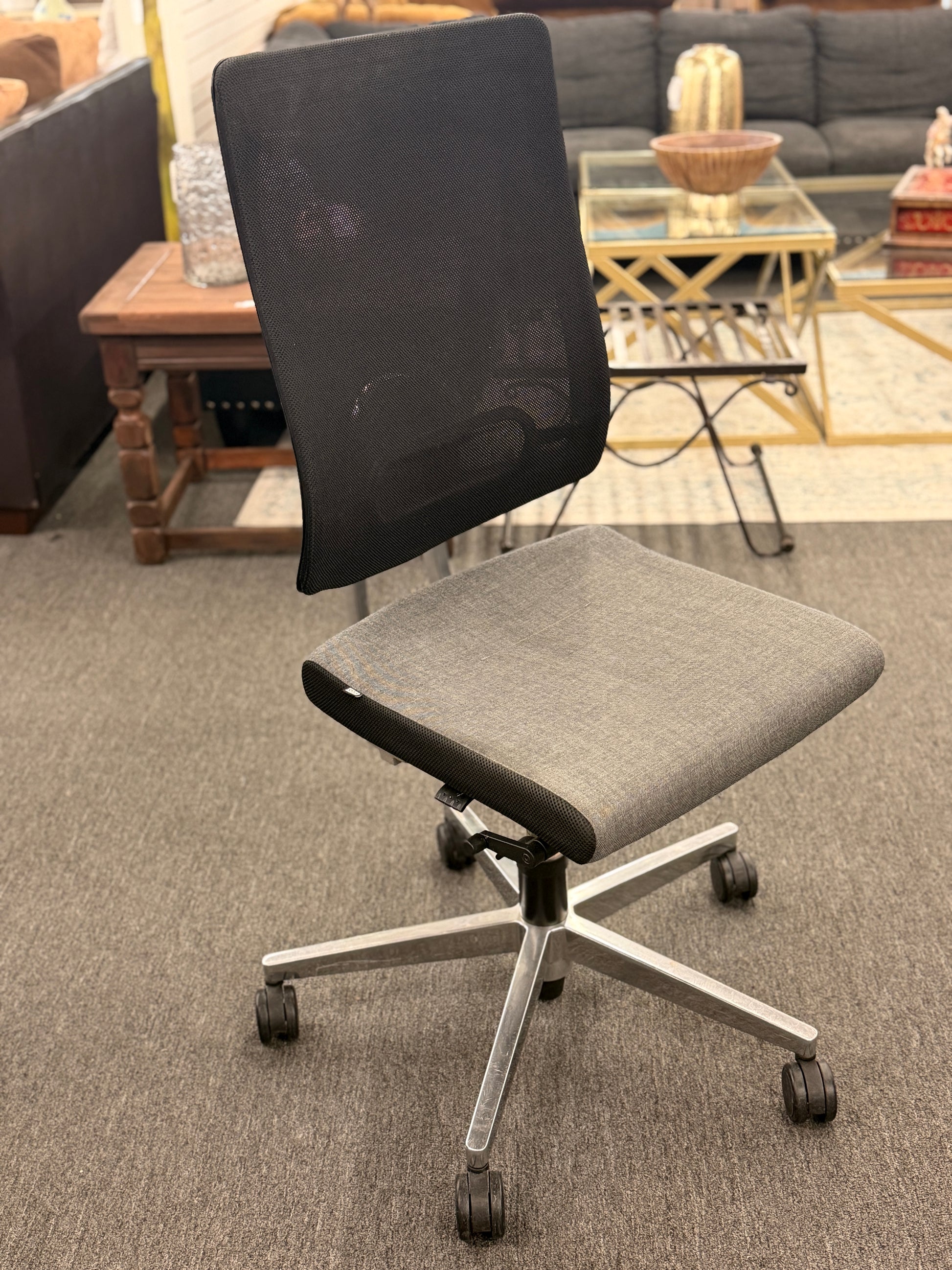 Gray office chair with black mesh back in a room with furniture and decor.