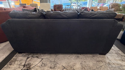 Large black sofa in a room with other furniture and decor.